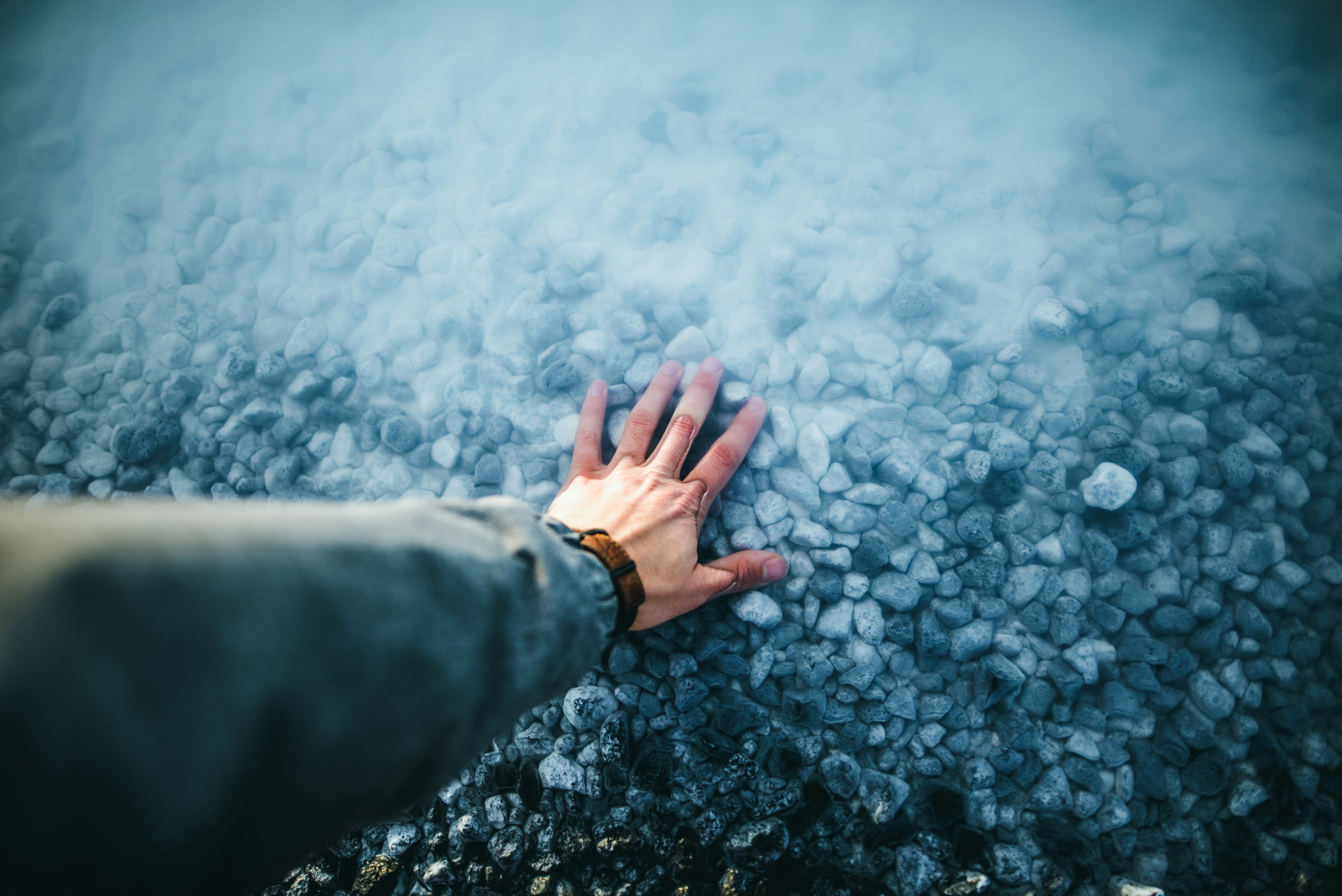Hand Resting on Misty Pebbles