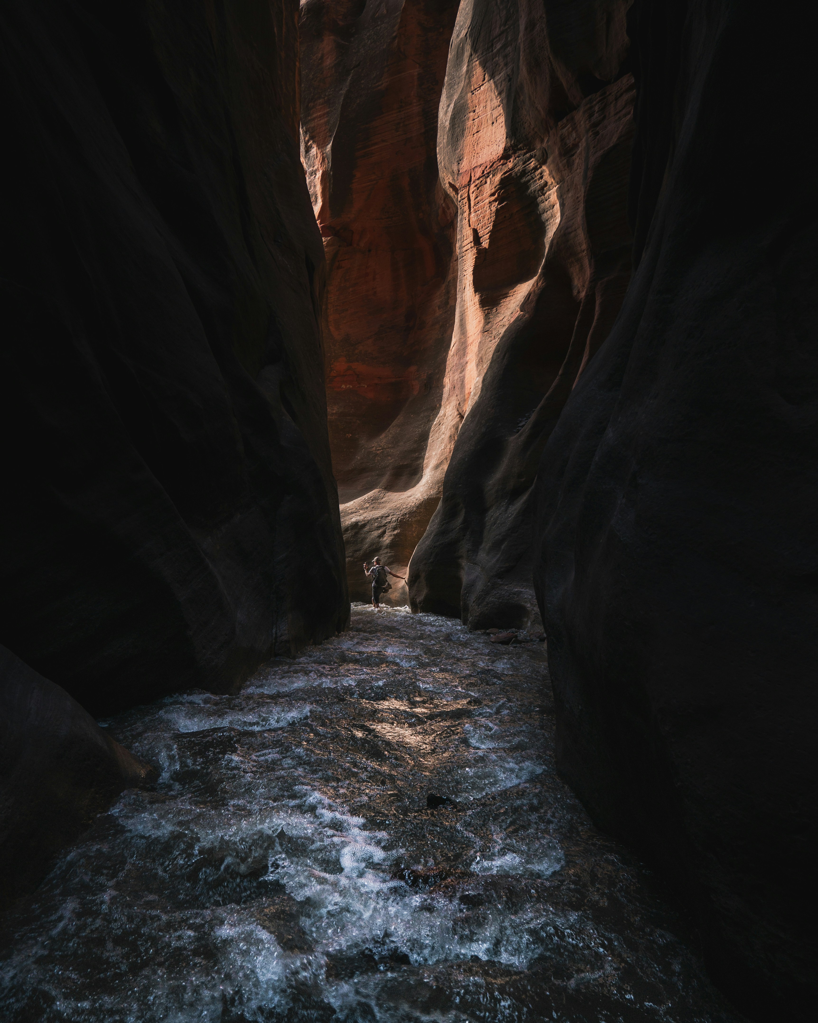 Hiker Wading in Narrow Canyon Stream