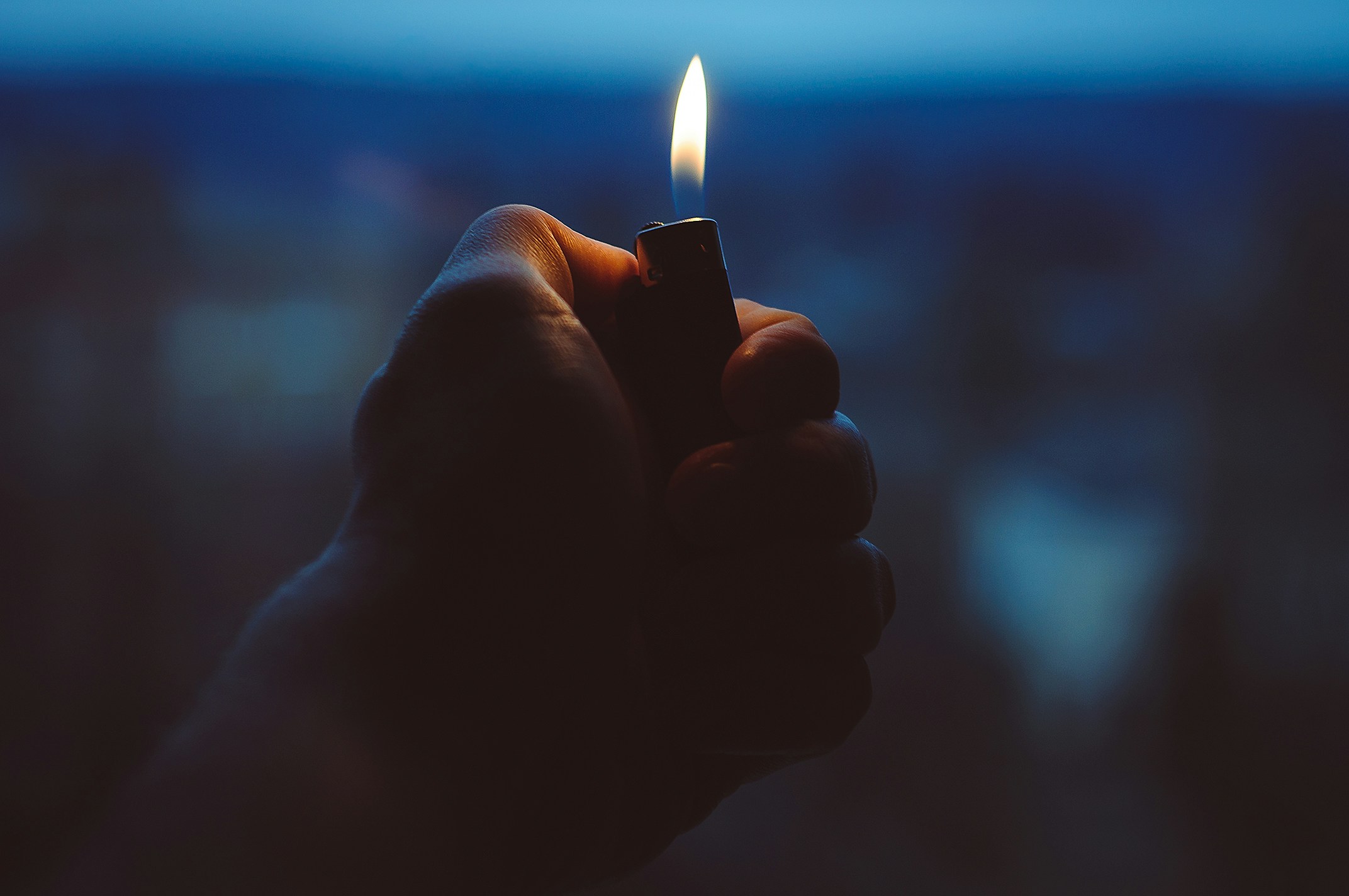 Hand Holding Lit Lighter at Dusk
