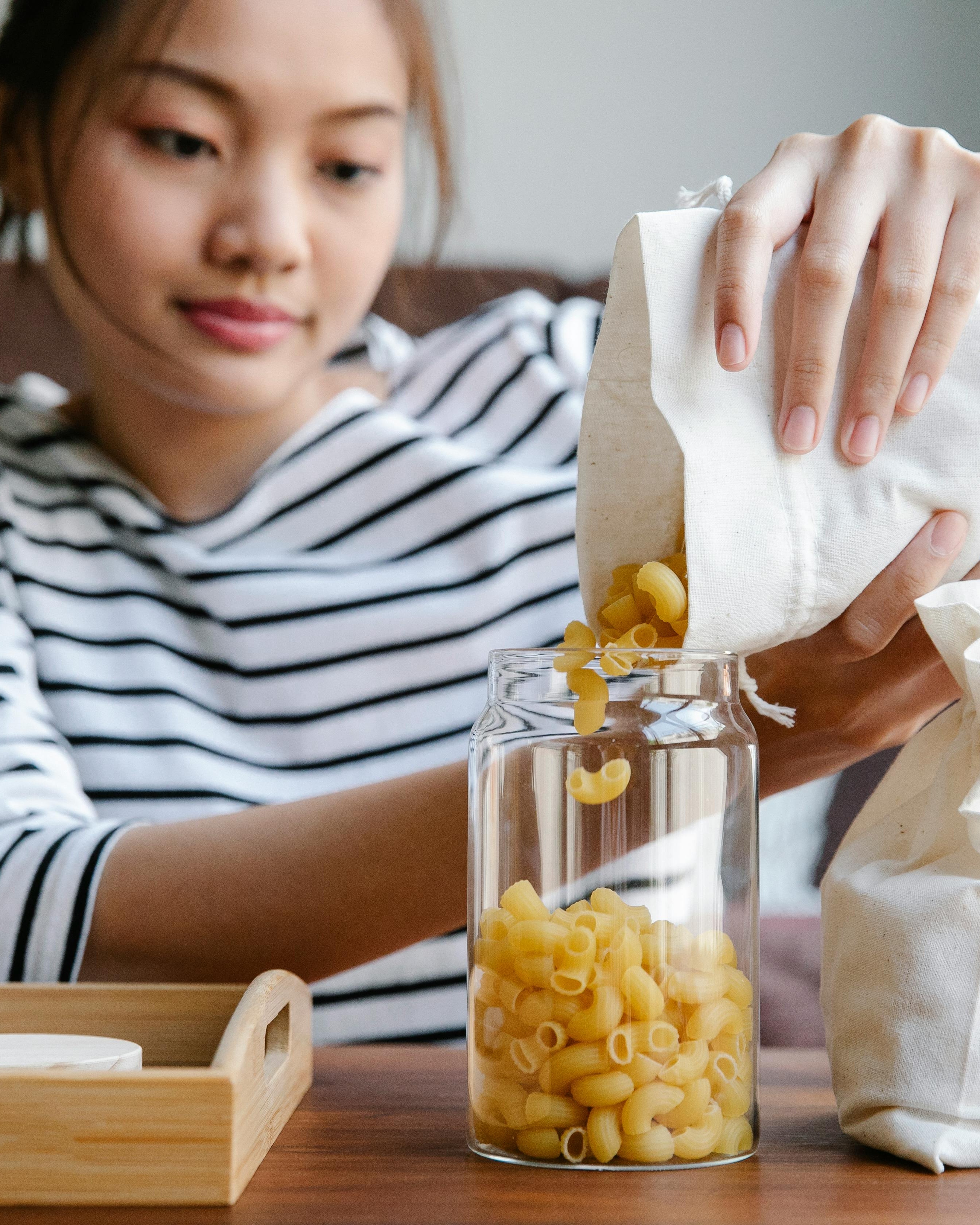 Pouring Dry Pasta Into Storage Jar