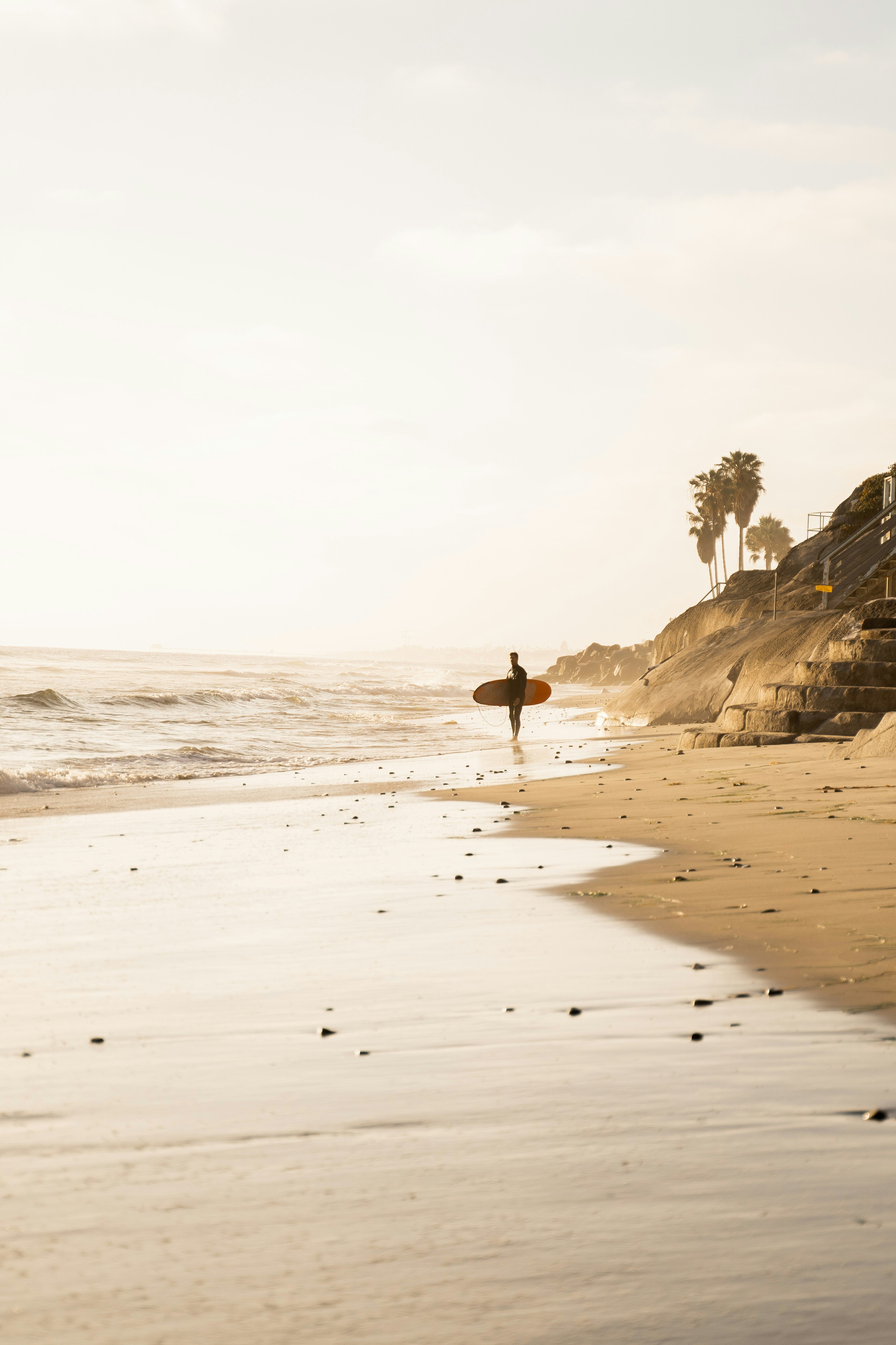 Surfer Walking Along Sandy Beach