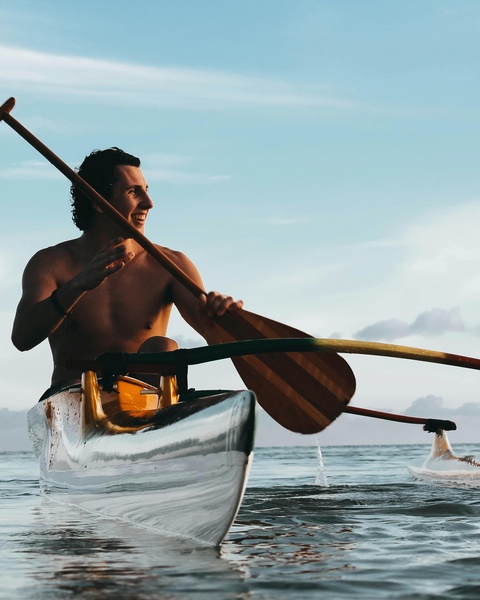 Man Paddling Outrigger Canoe on Ocean