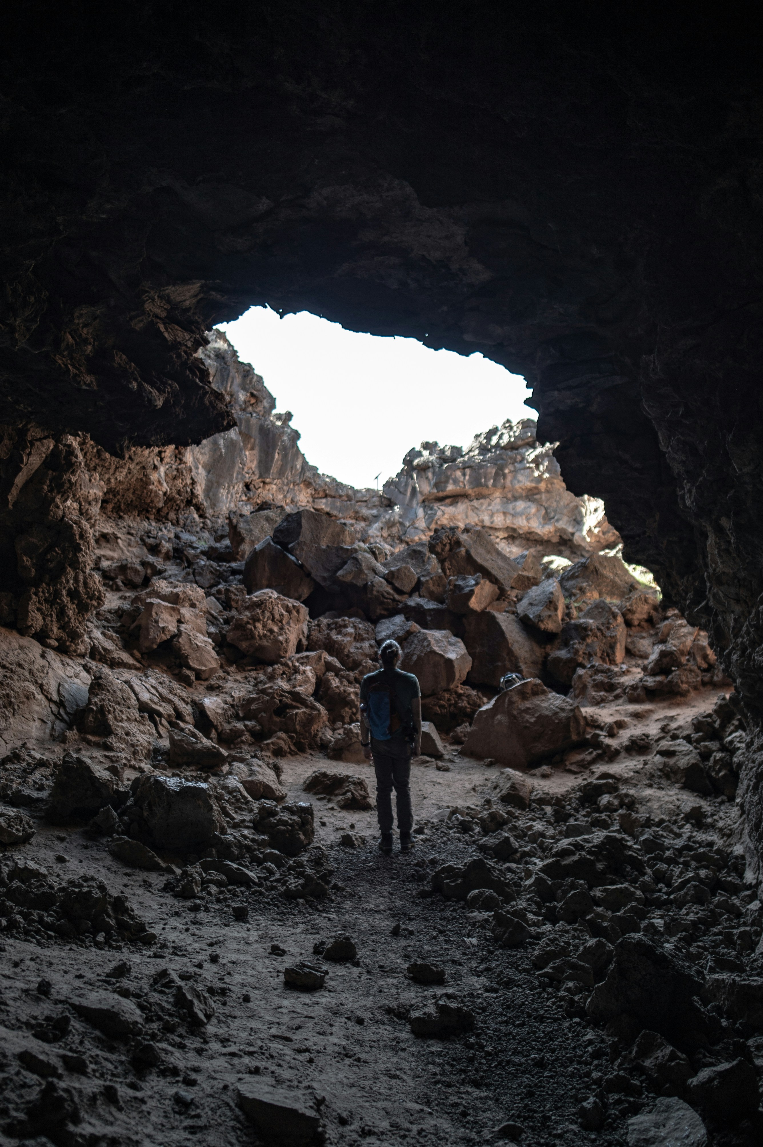 Hiker Standing Inside Cave Facing Exit