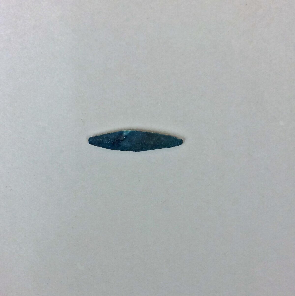 Dark Elongated Arrowhead on Plain Background