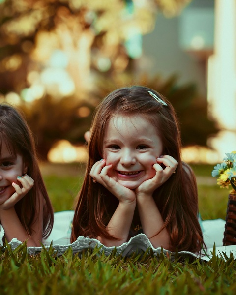 Two Smiling Girls Lying on Grass