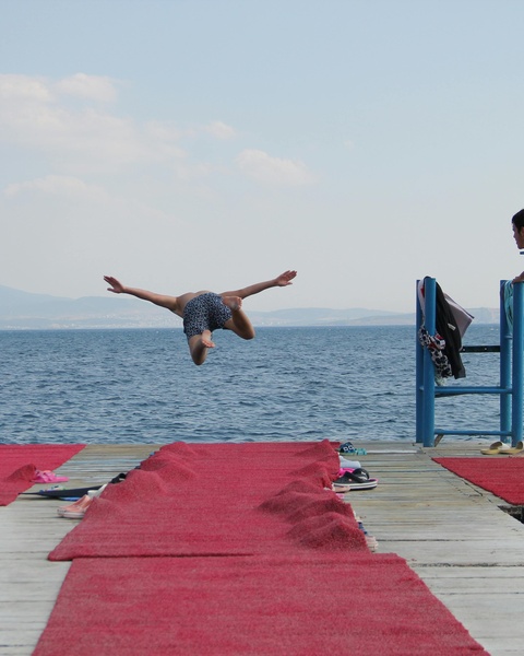 Person Jumping Into Sea From Dock