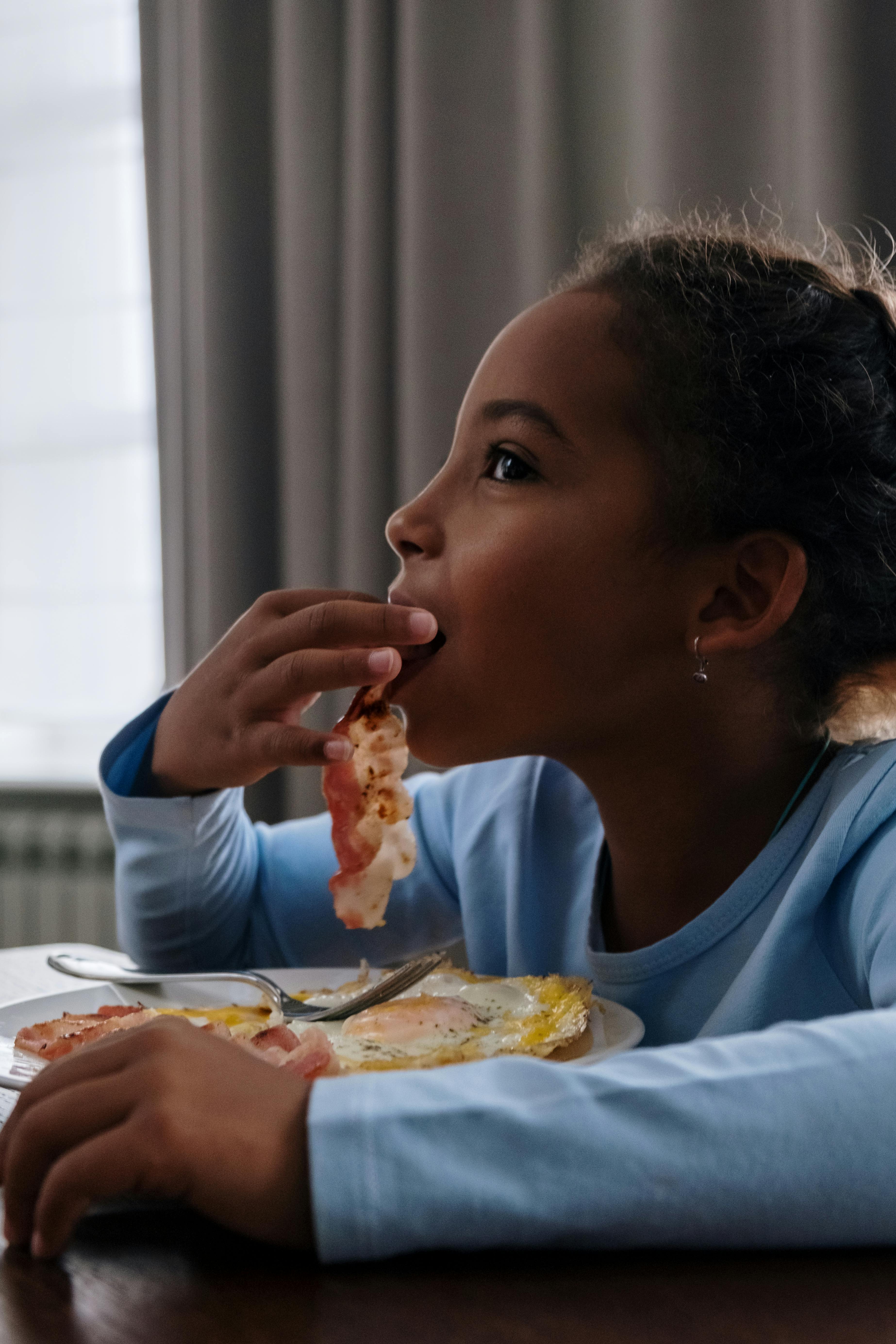 Young Girl Eating Bacon for Breakfast