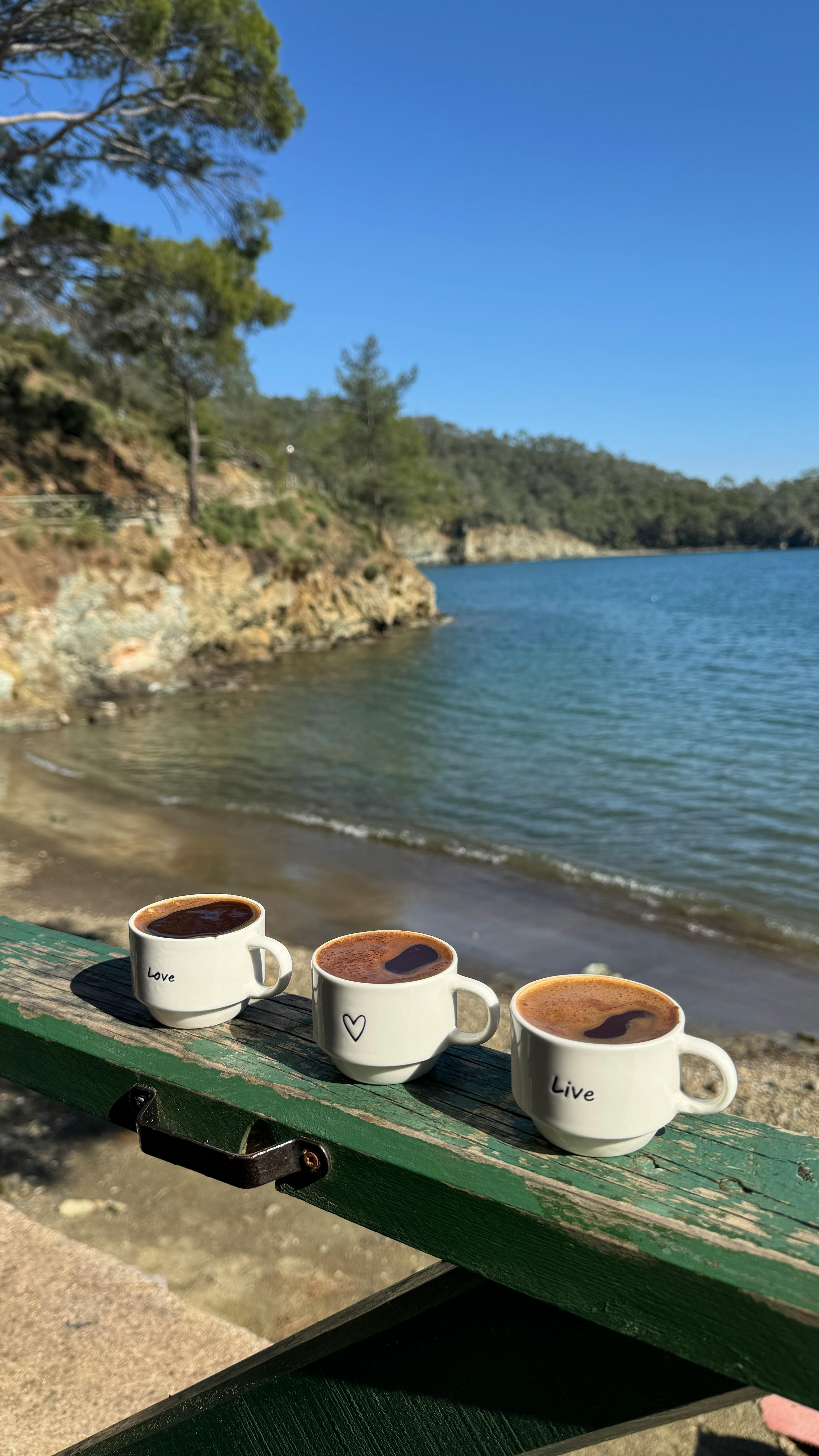 Three Coffee Mugs By A Lake