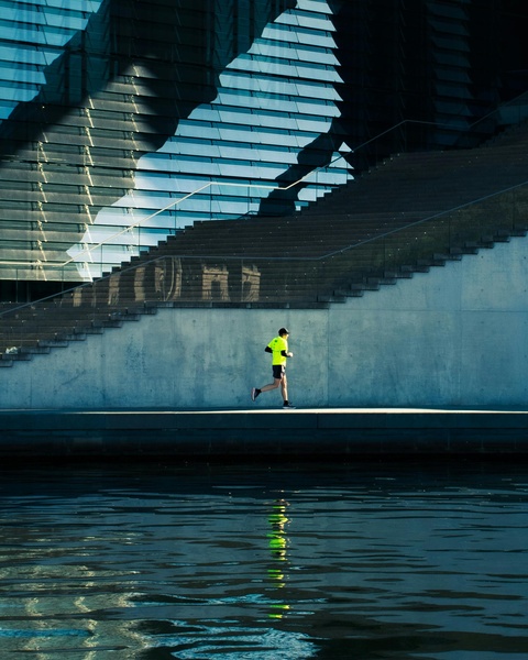 Jogger Running by Modern Waterfront Building