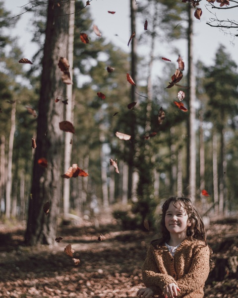 Girl Watching Falling Autumn Leaves in Forest