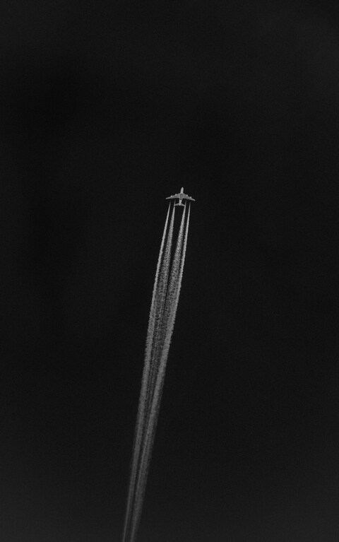 Airplane with Contrails Against Dark Sky