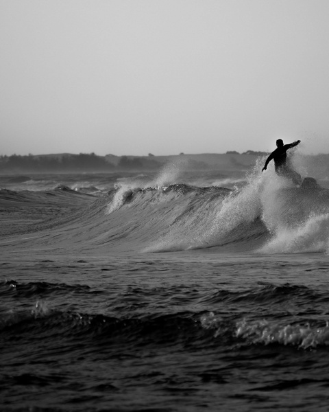 Silhouetted Surfer Riding Ocean Wave