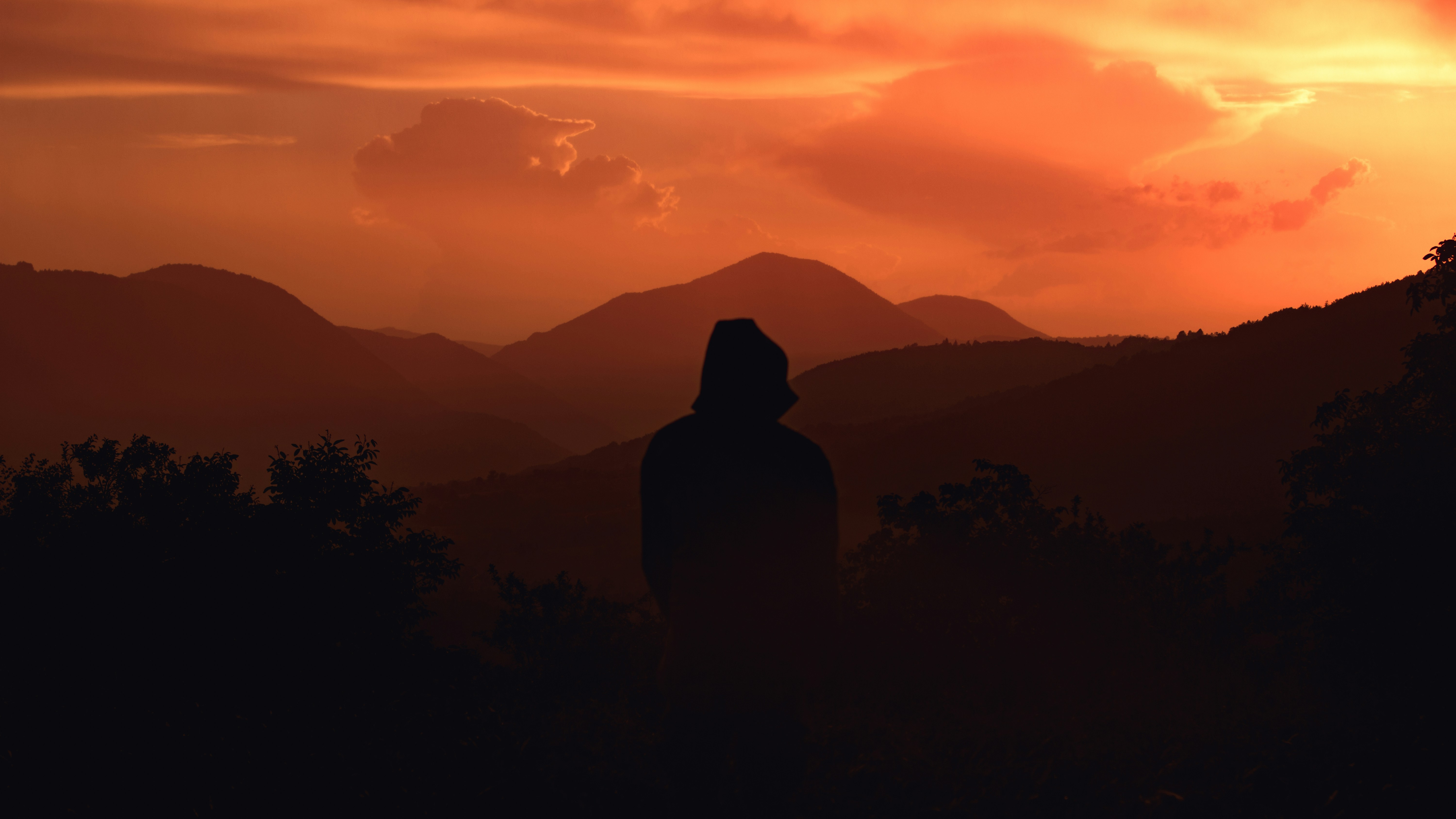 Hooded Figure Watching Mountain Sunset