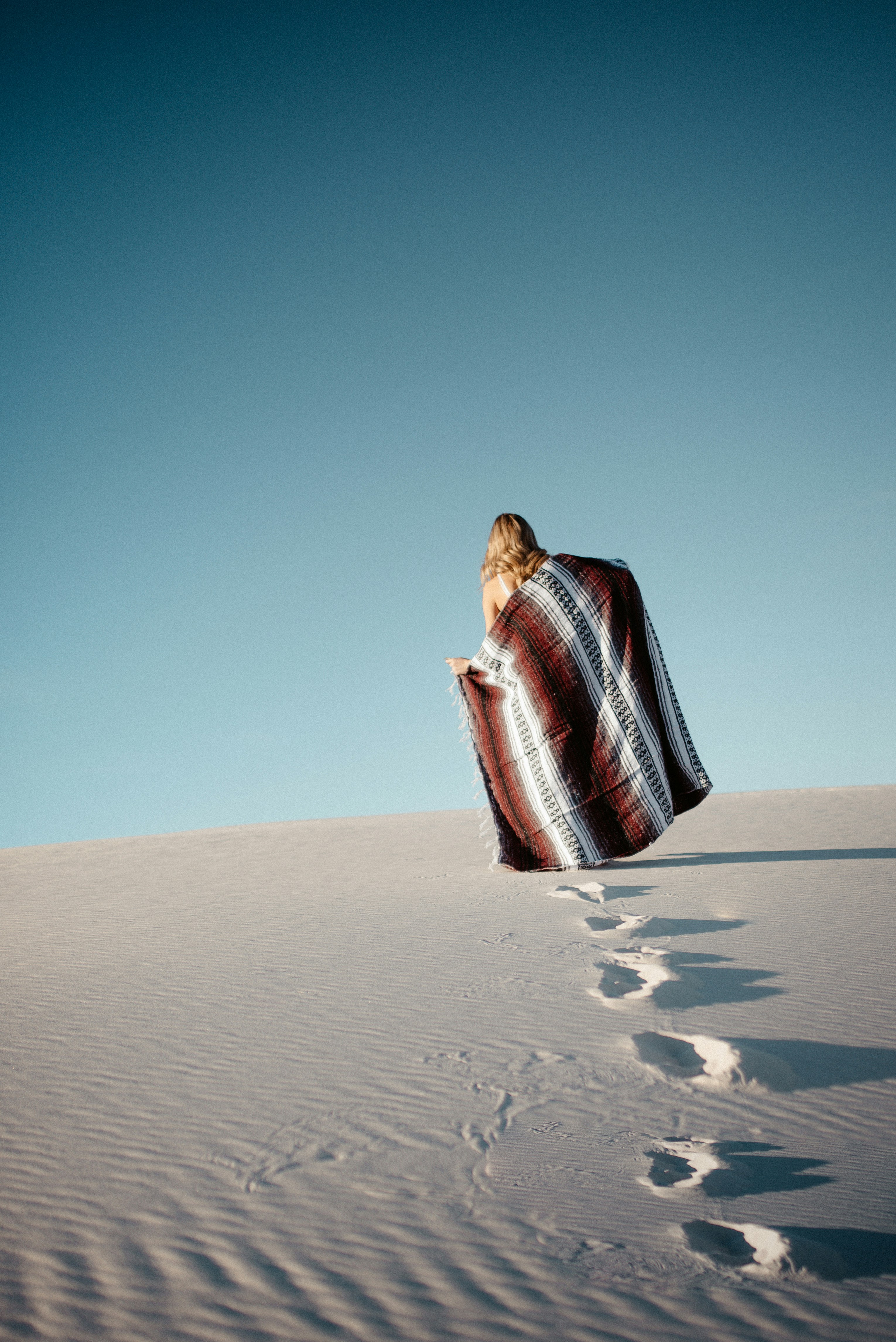 Woman Walking Up White Sand Dune
