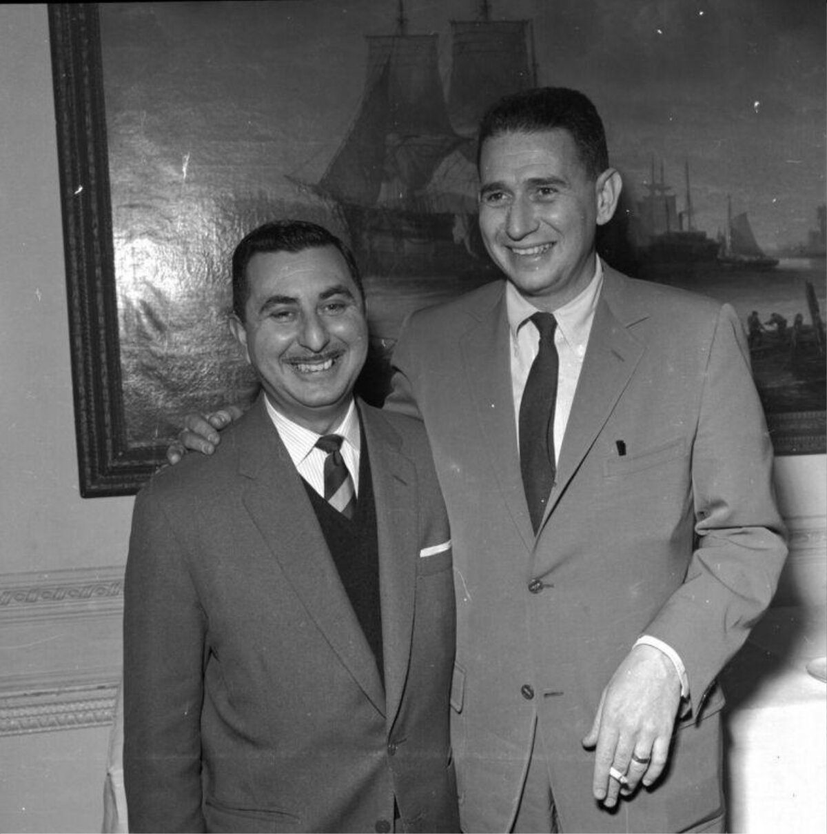 Two Smiling Men In Suits Posing Together