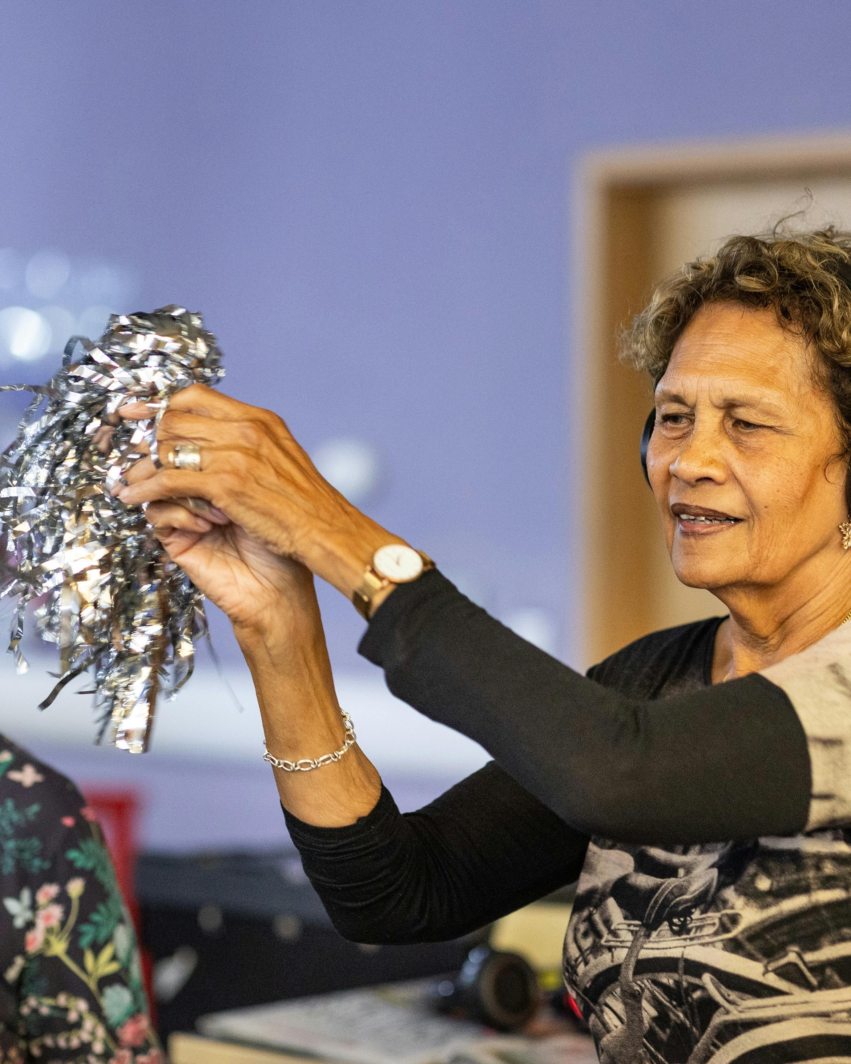 Older Woman Holding Silver Pom Pom