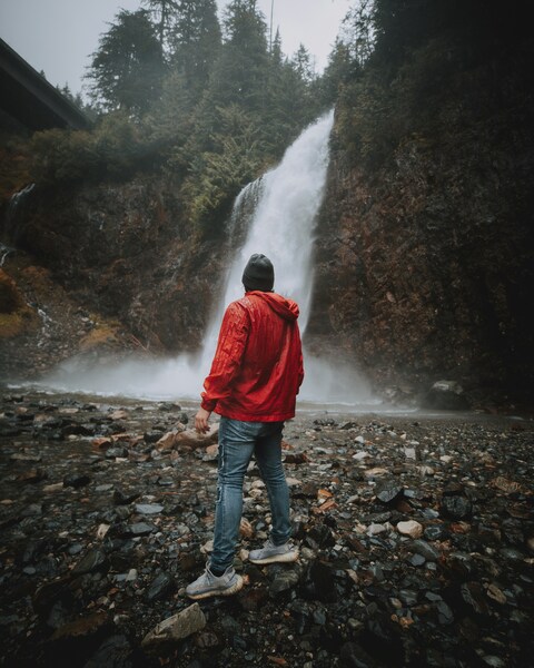 Man Standing Before Forest Waterfall