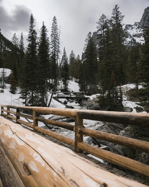 Wooden Bridge Over Snowy Mountain Stream