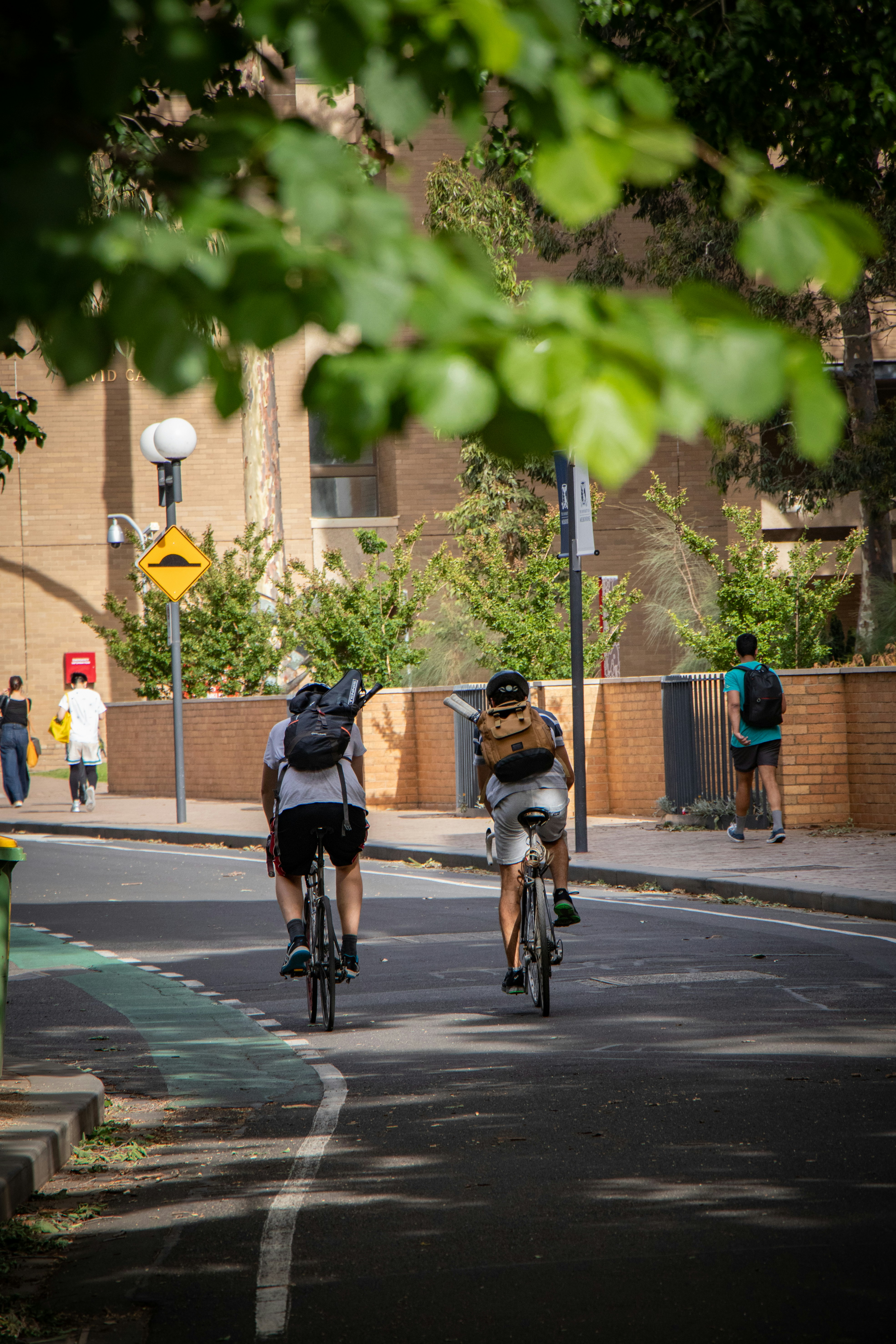 Two Cyclists Riding on Campus Road