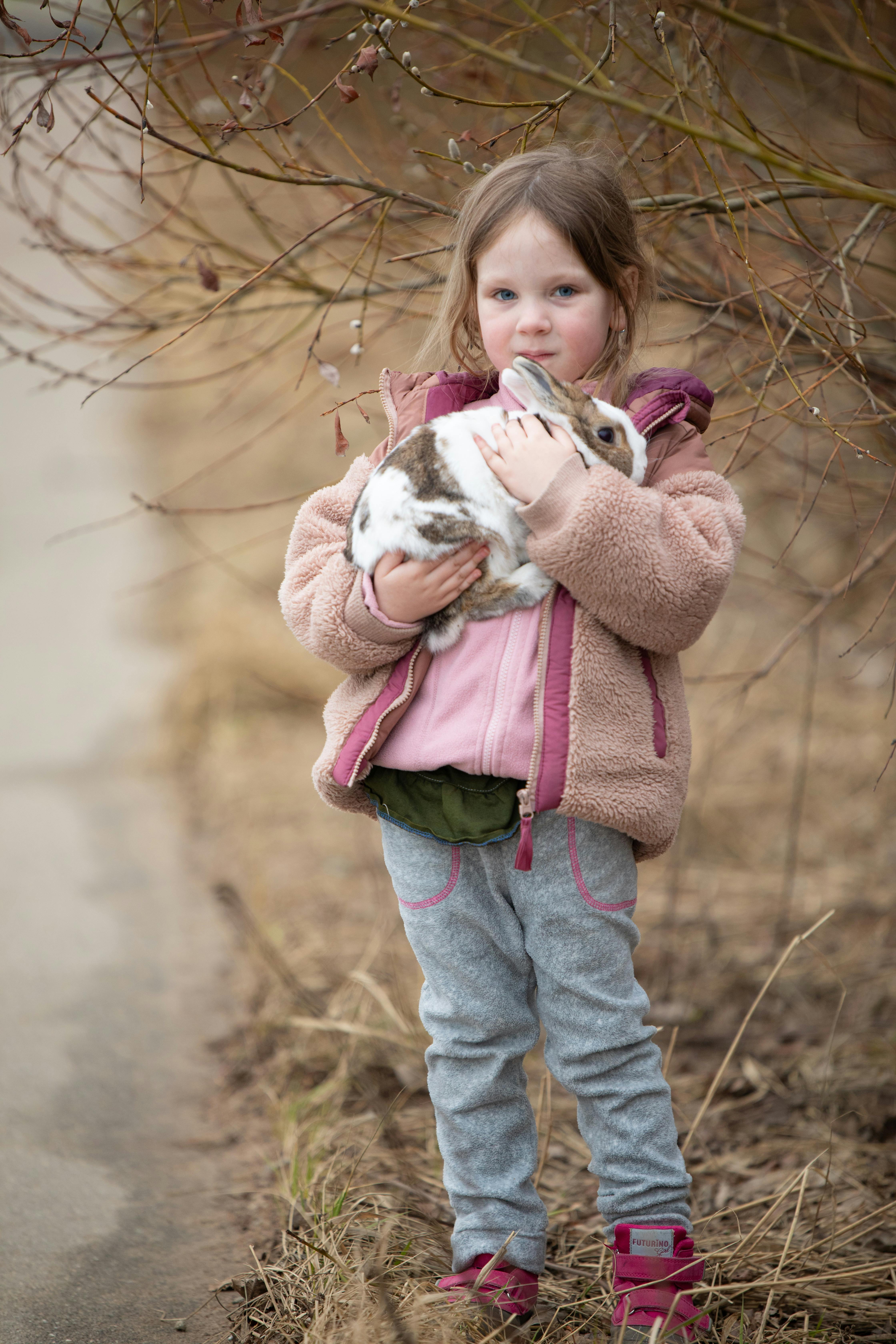 Little Girl Holding Pet Rabbit Outdoors
