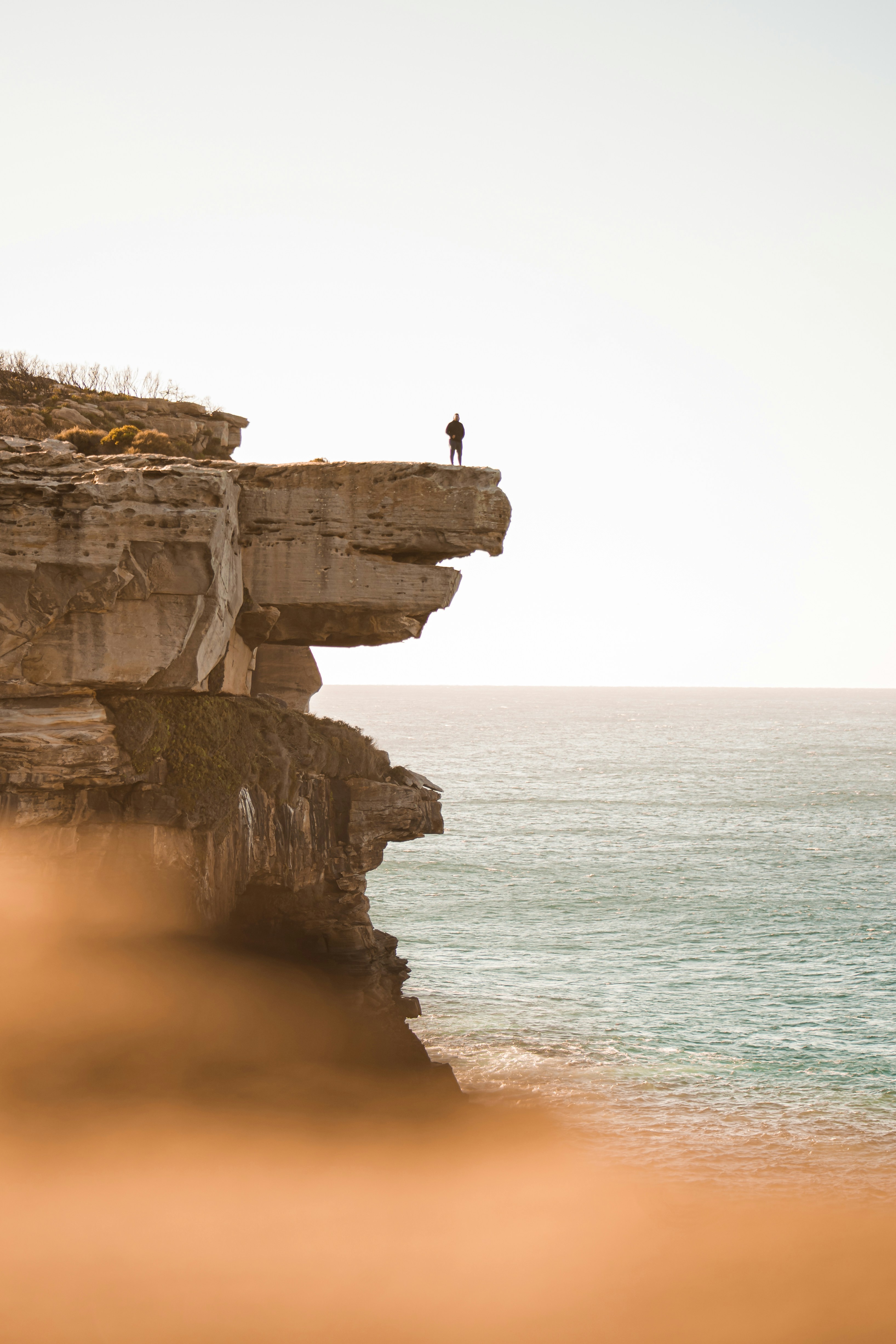 Lone Person on Coastal Cliff by Sea