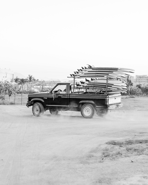 Pickup Truck Hauling Surfboards On Dirt Road