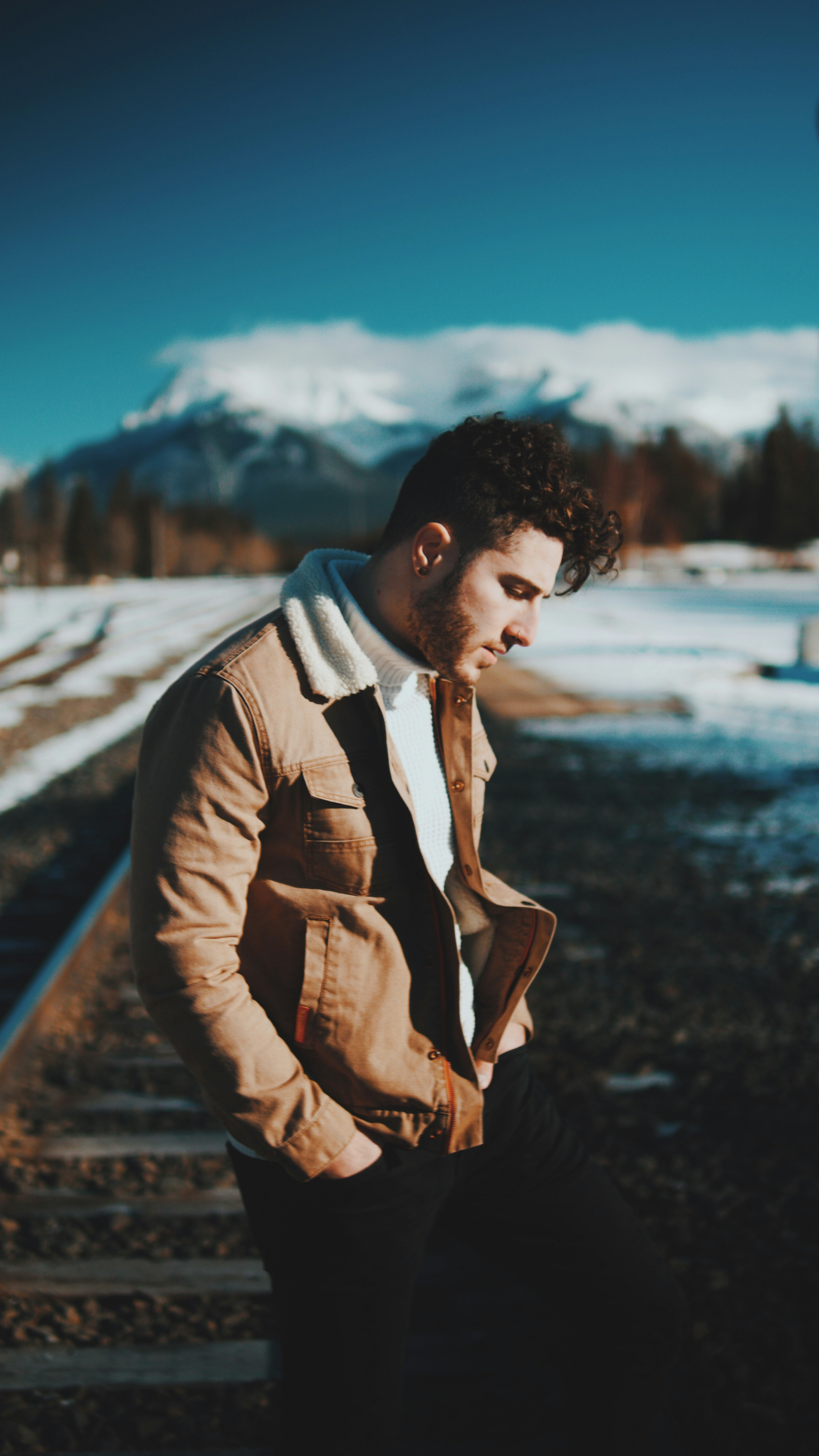 Man on Snowy Railway By Mountains