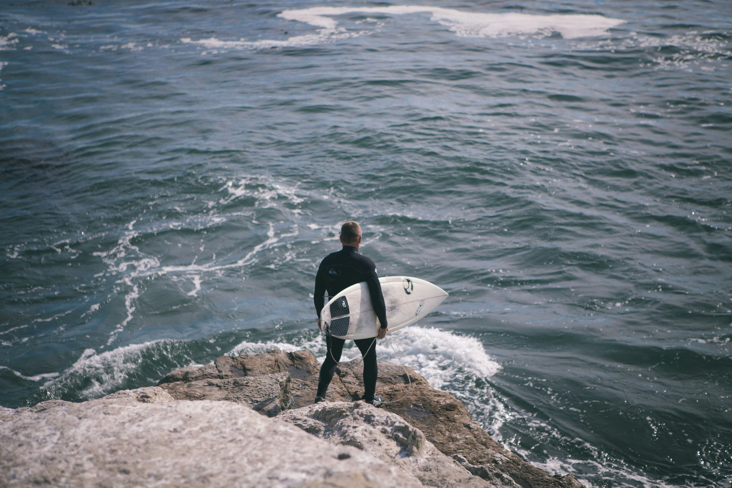 Surfer on Cliff Overlooking Sea