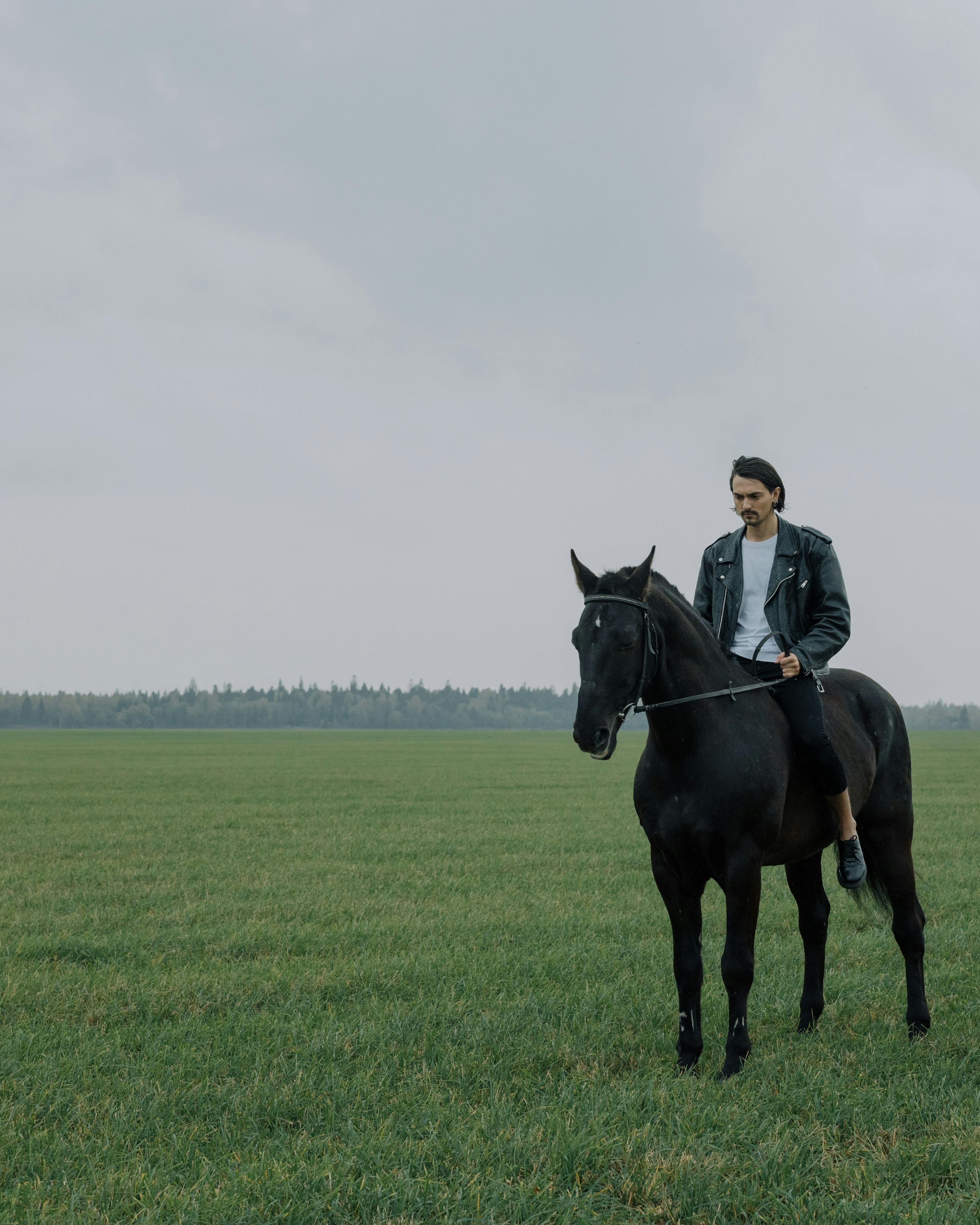 Man Riding Black Horse in Open Field