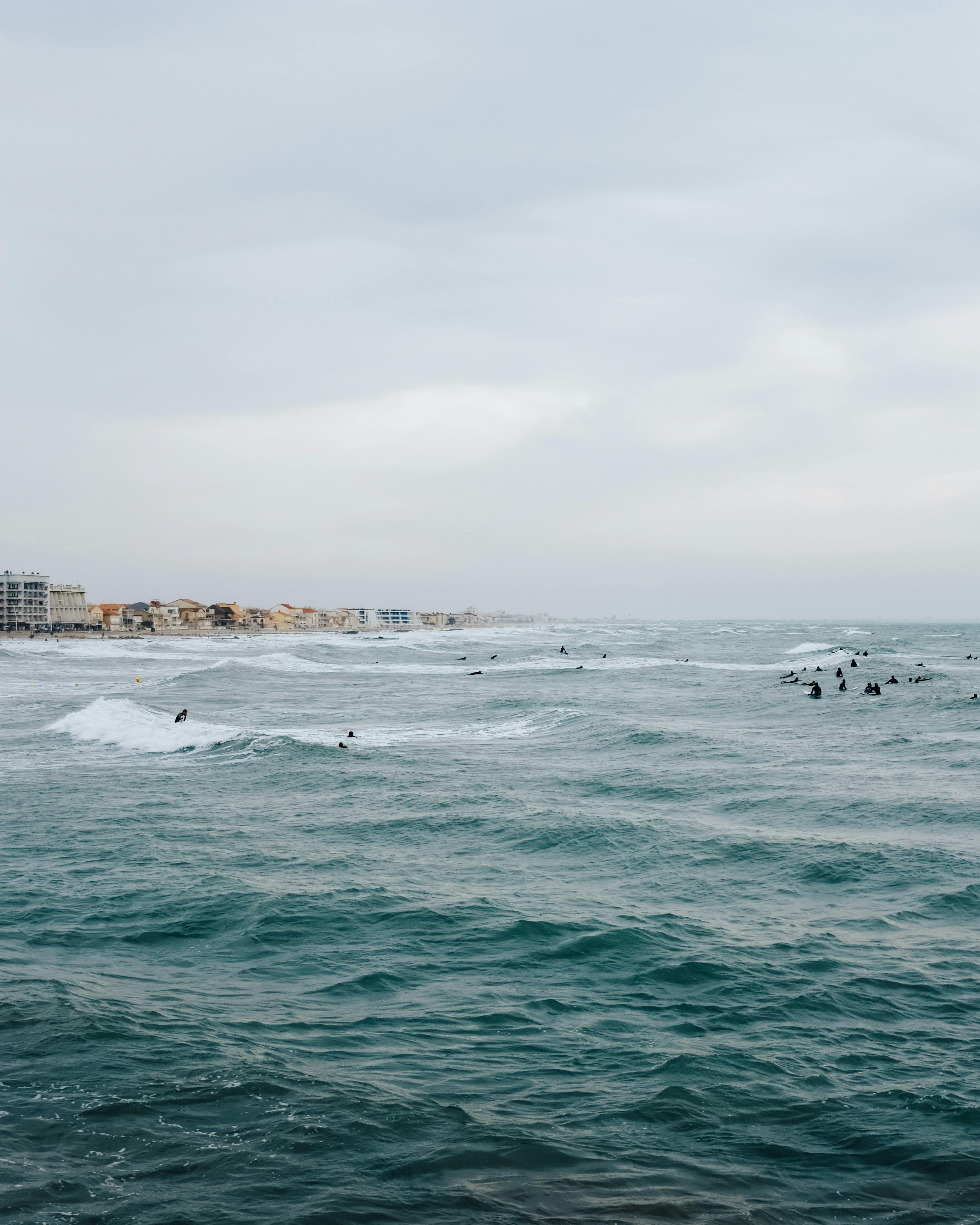 Surfers in Ocean Near Coastal Town