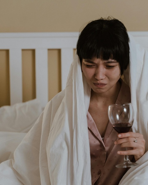 Crying Woman Holding Wine in Bed