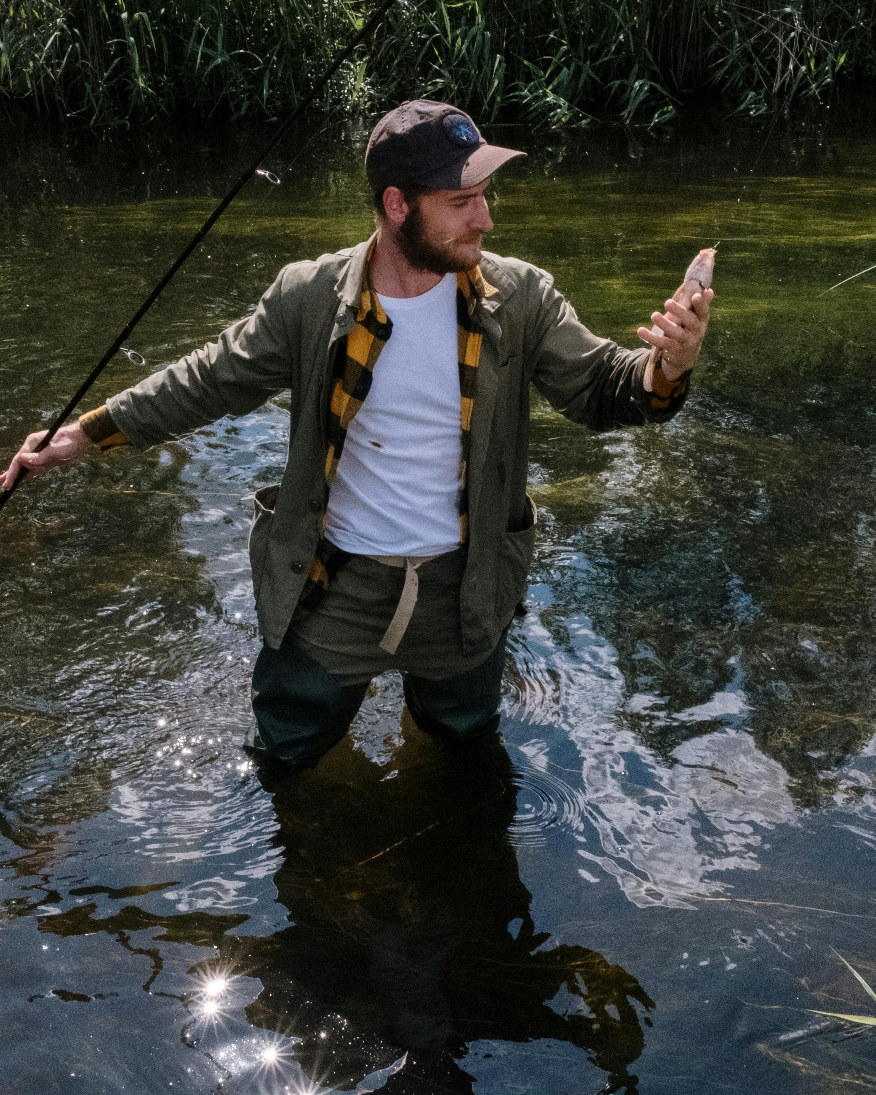 Fisherman Holding Caught Fish While Wading In River
