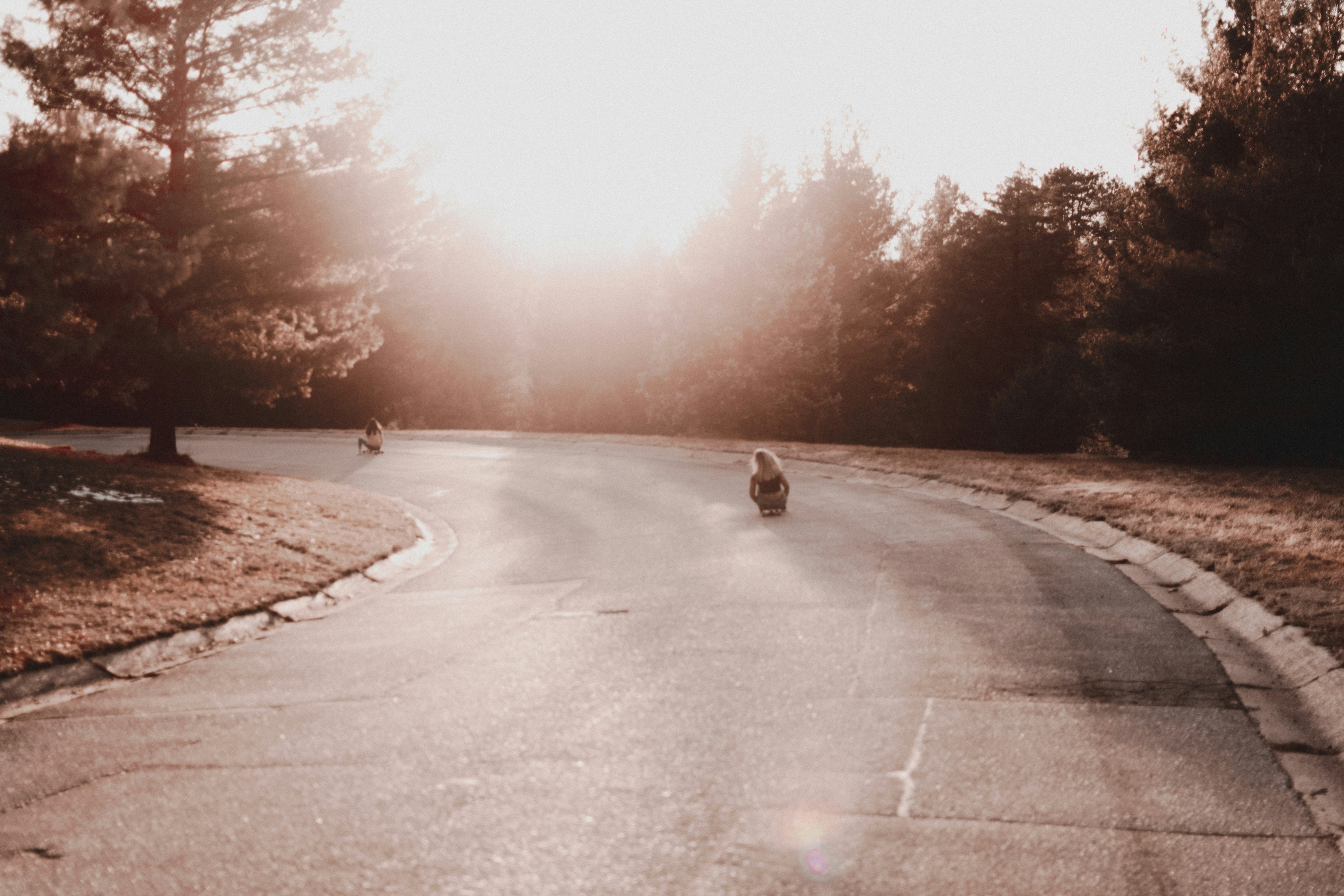 Two Girls Skateboarding Down Sunset Road