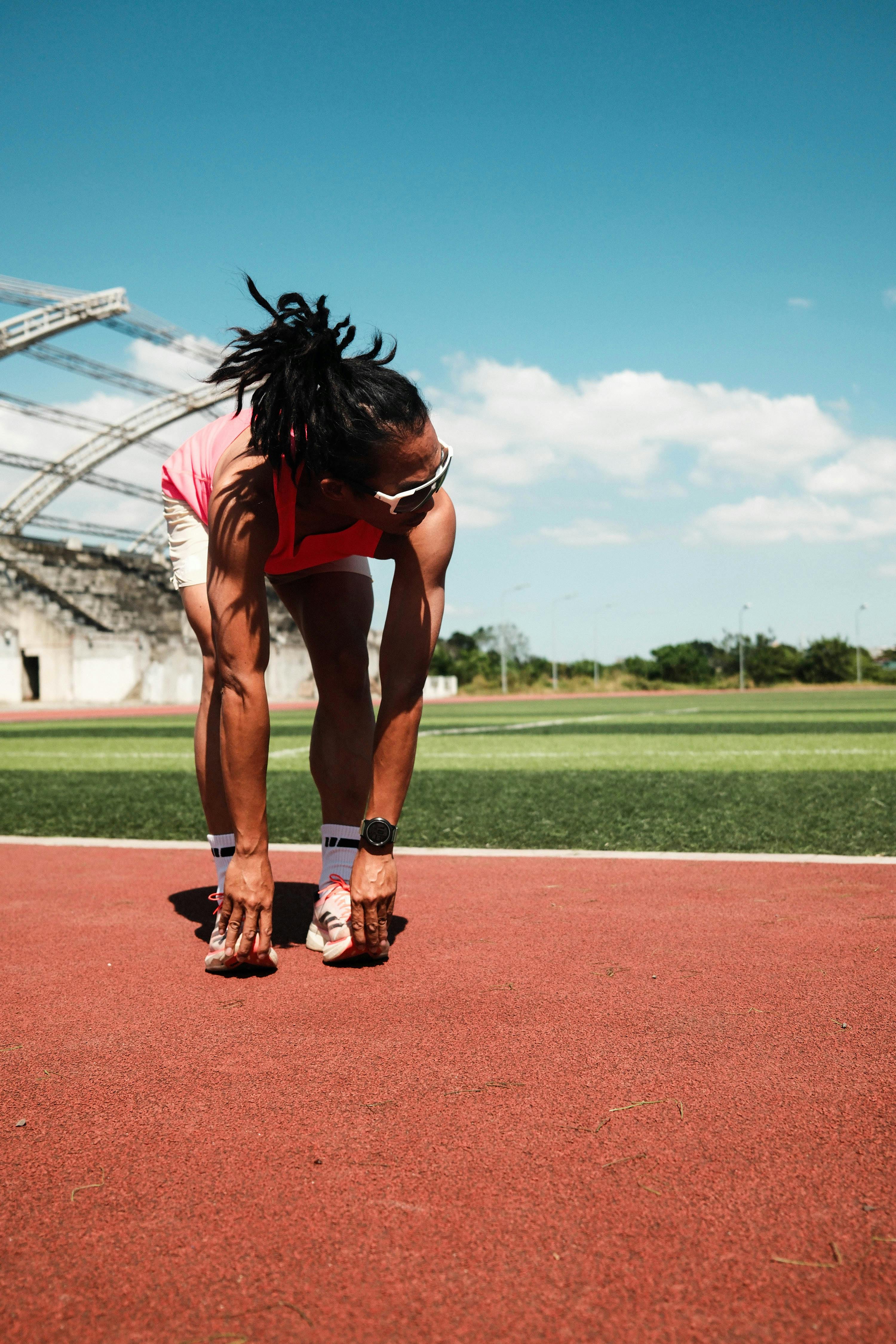 Athlete Stretching on Stadium Running Track