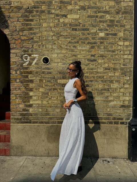 Woman in White Dress Against Brick Wall