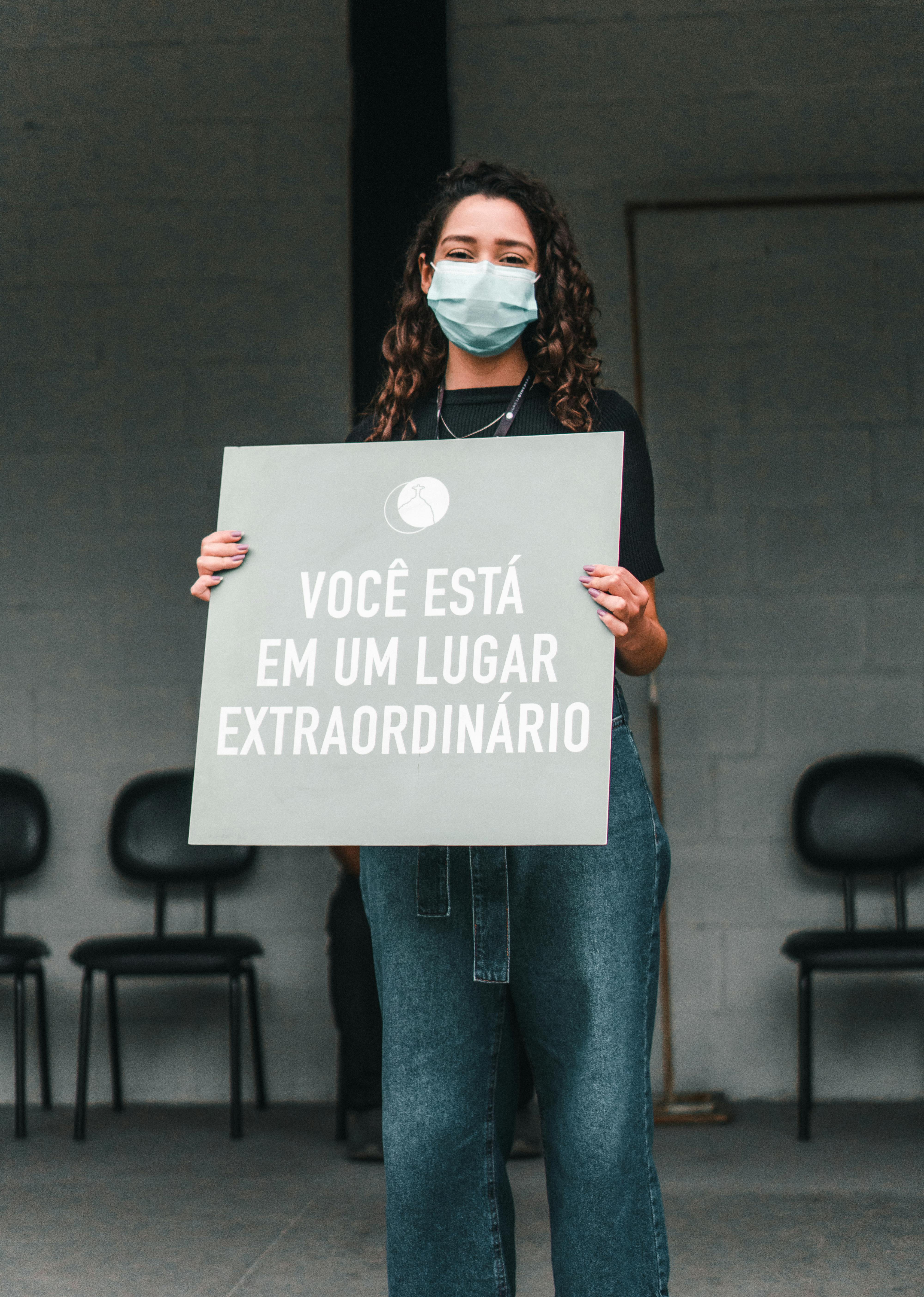 Masked Woman Holding Greeting Sign