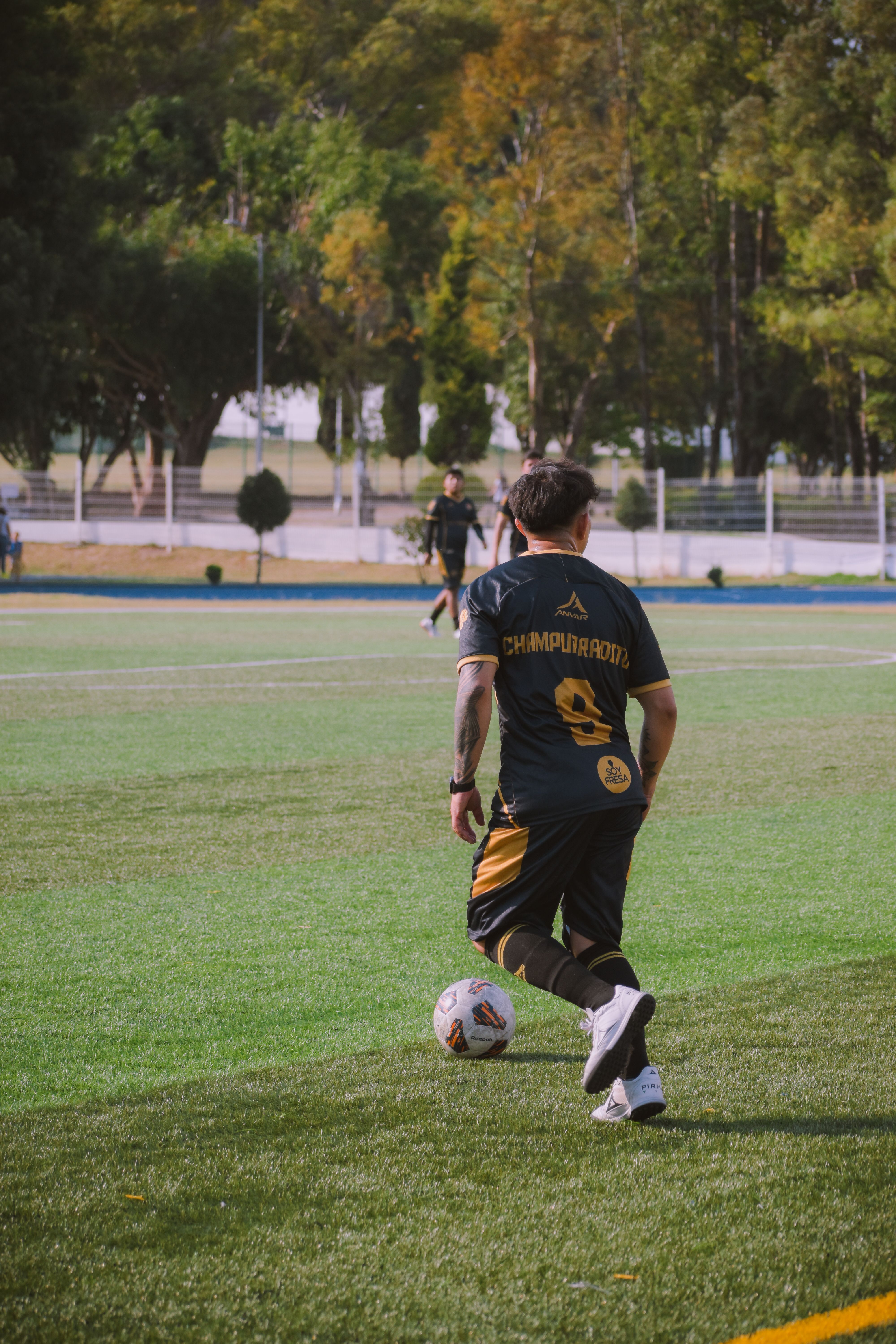 Soccer Player Dribbling on Green Field