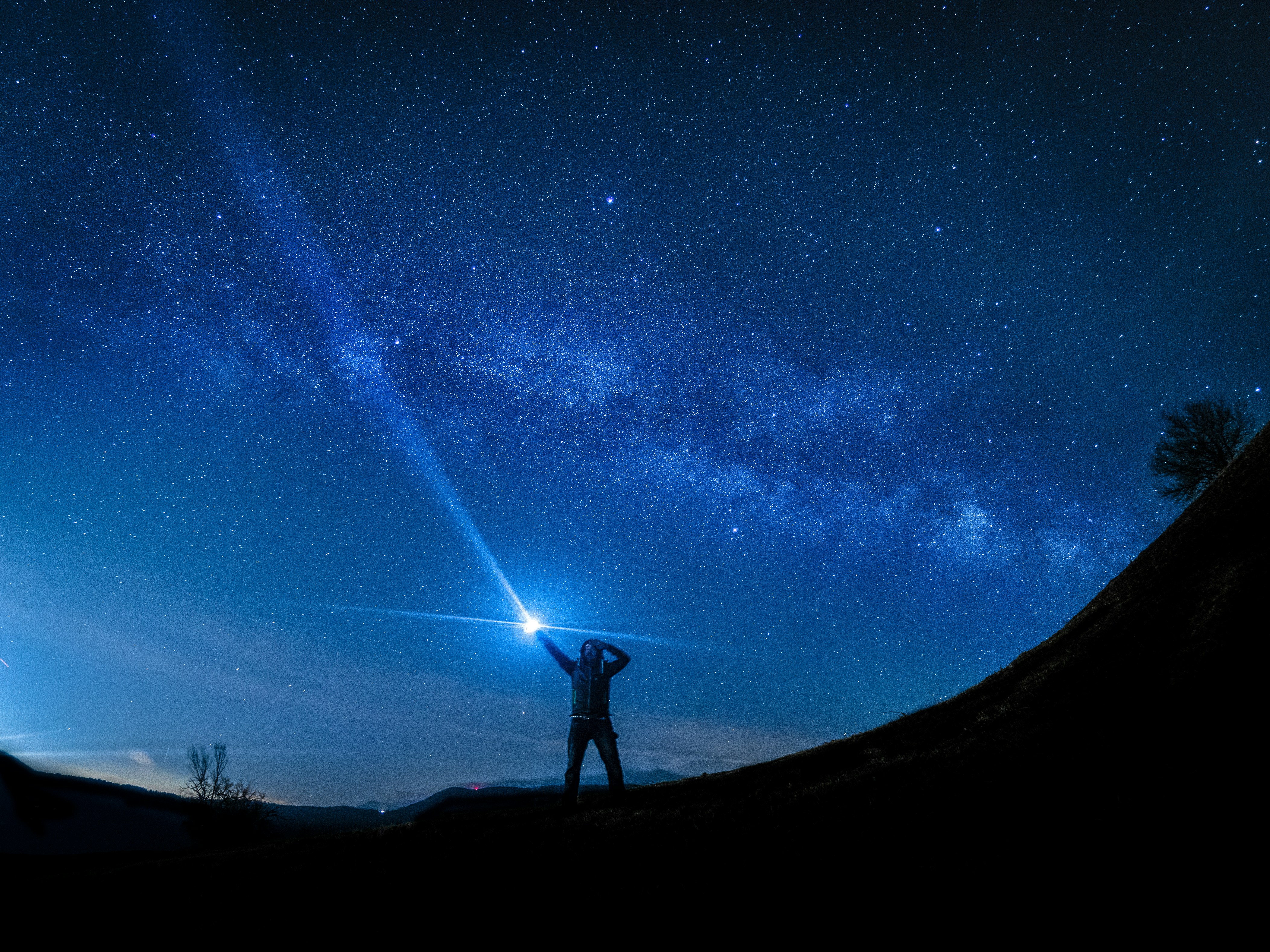 Person Holding Flashlight Under Starry Sky