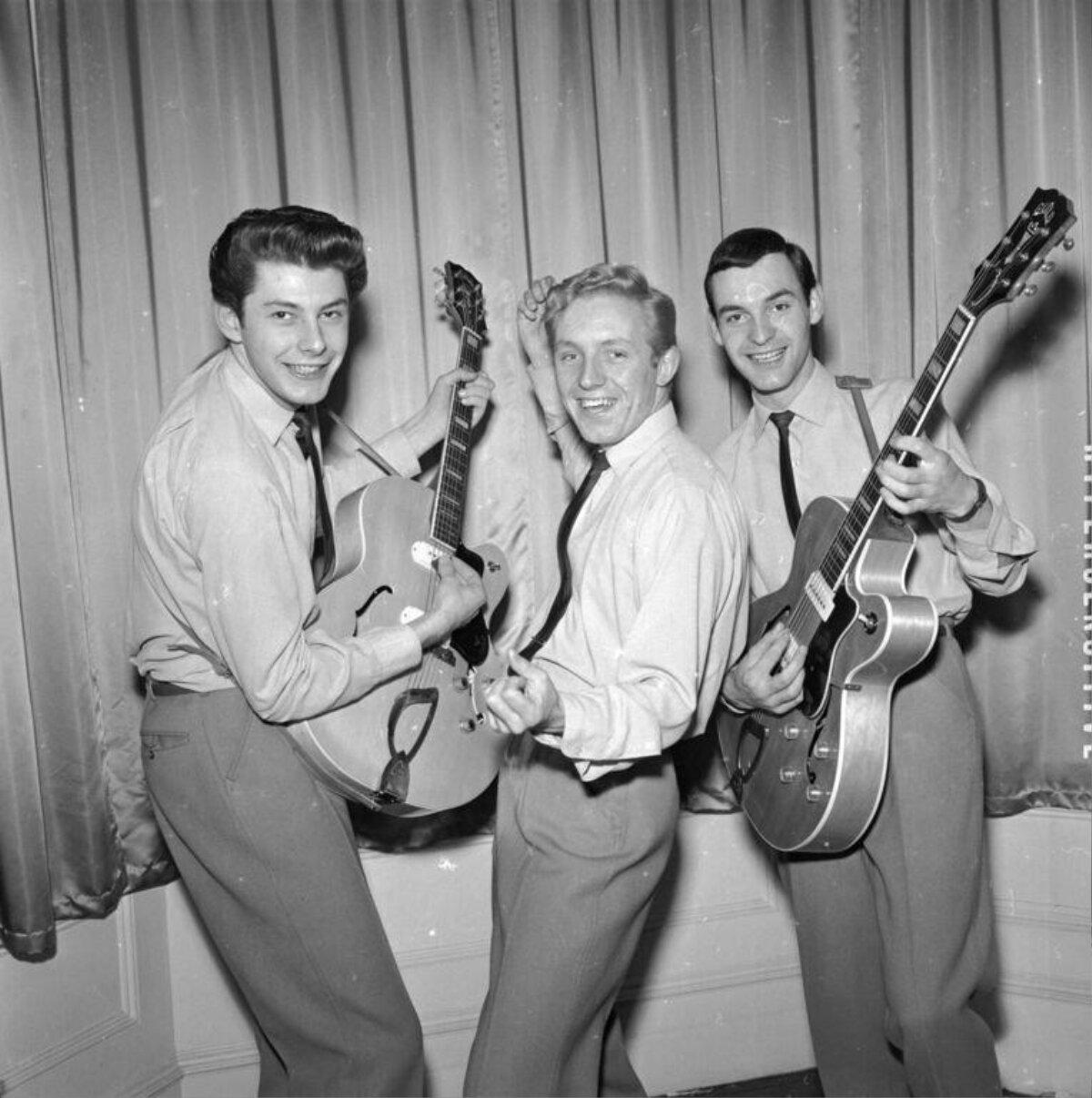 Three Musicians Posing With Guitars