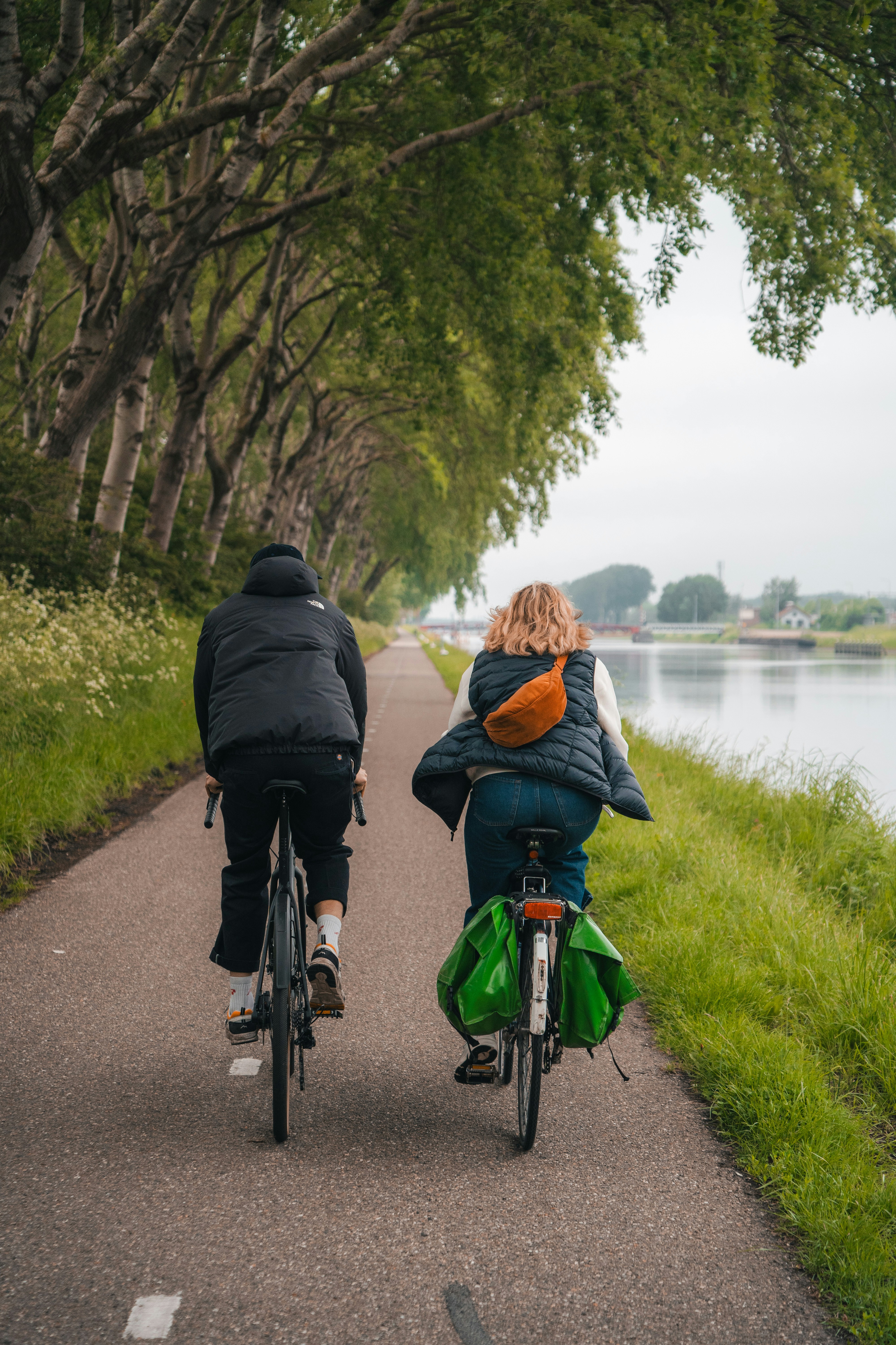 Two People Cycling Along Canal Path