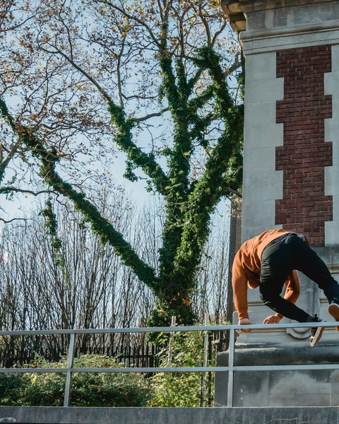 Man Climbing Over Railing By Brick Building