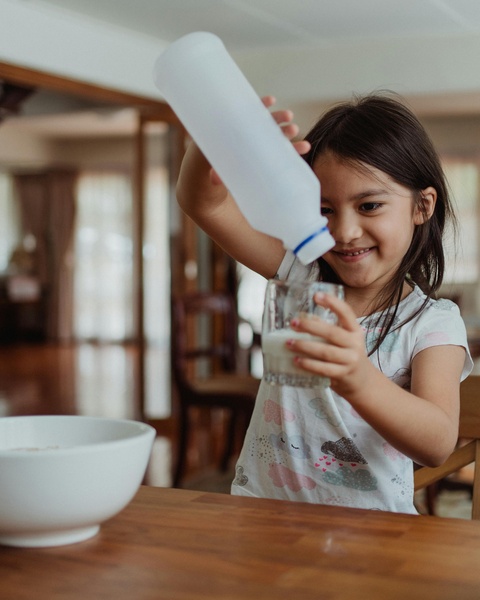 Little Girl Pouring Milk Into Glass