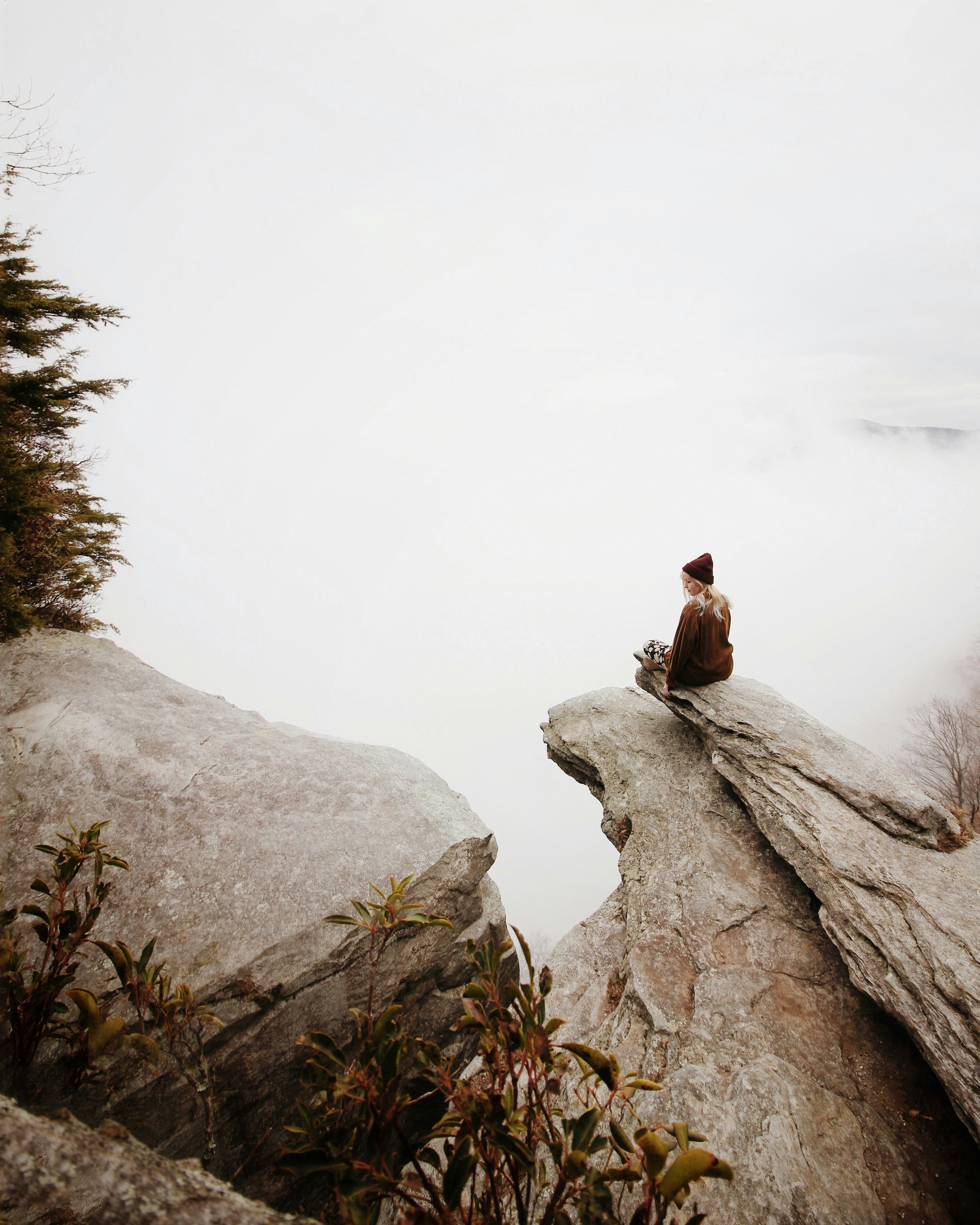 Woman Sitting on Foggy Mountain Cliff