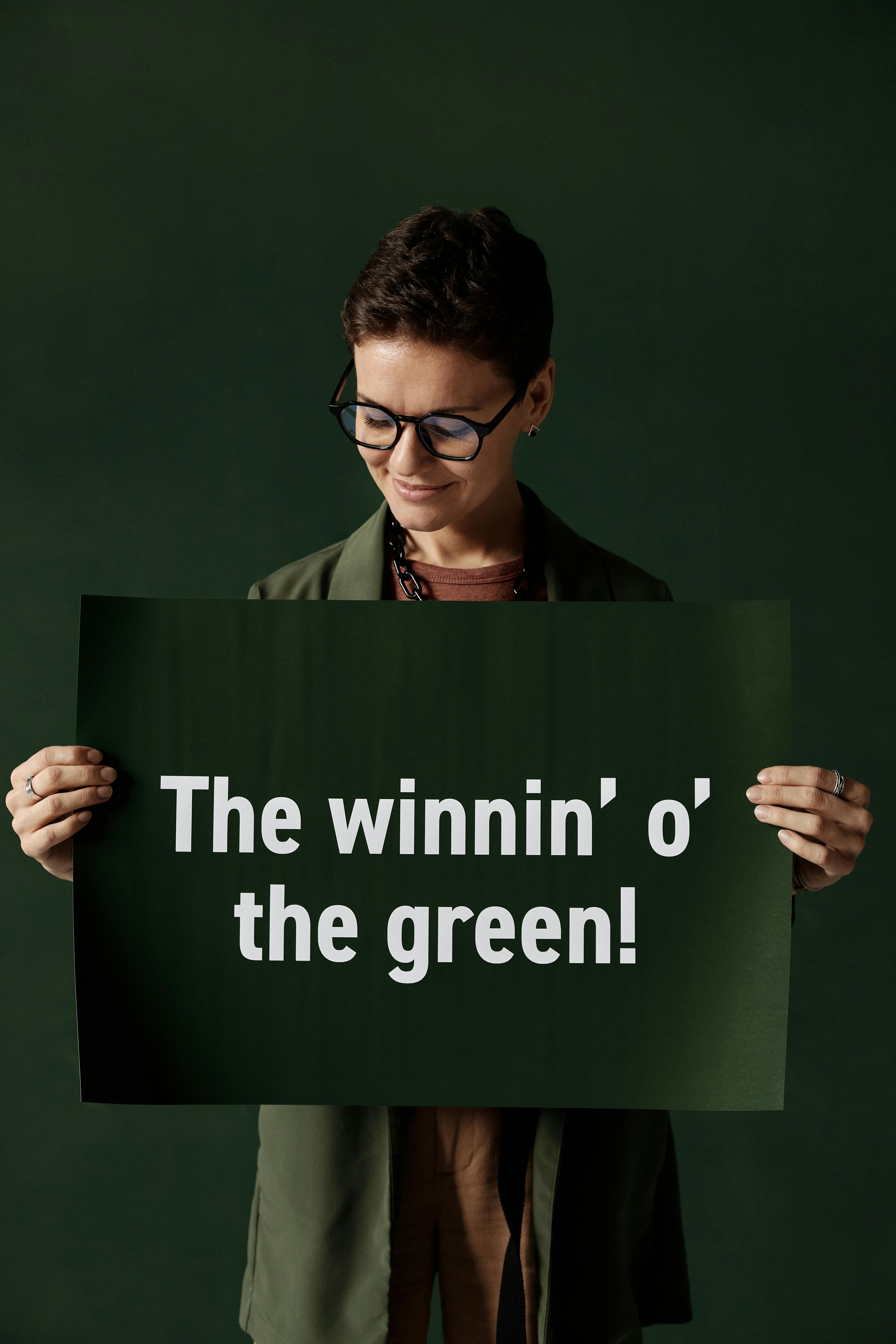 Woman Holding 'The winnin' o' the green' Sign
