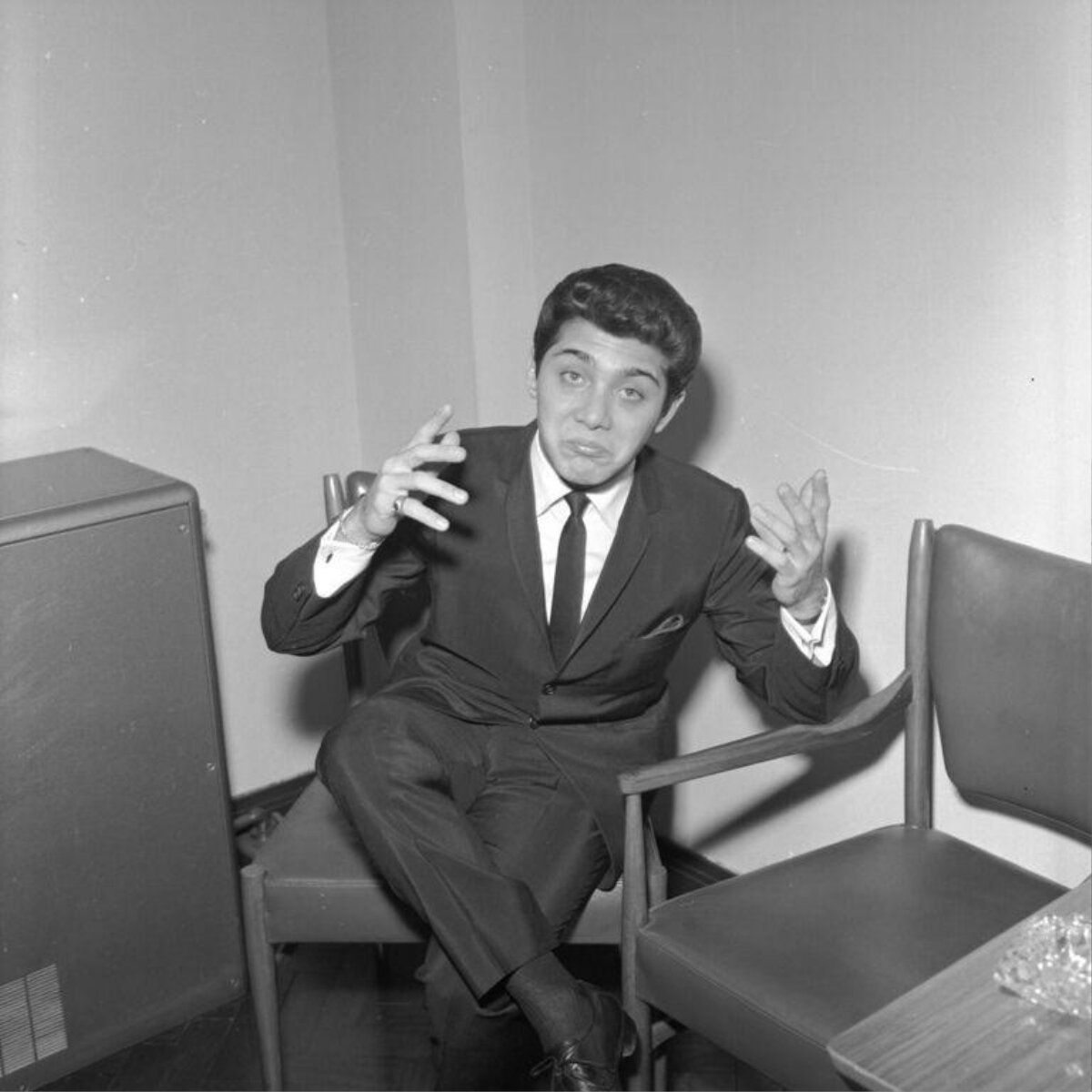 Gesturing Man In Suit Seated Indoors
