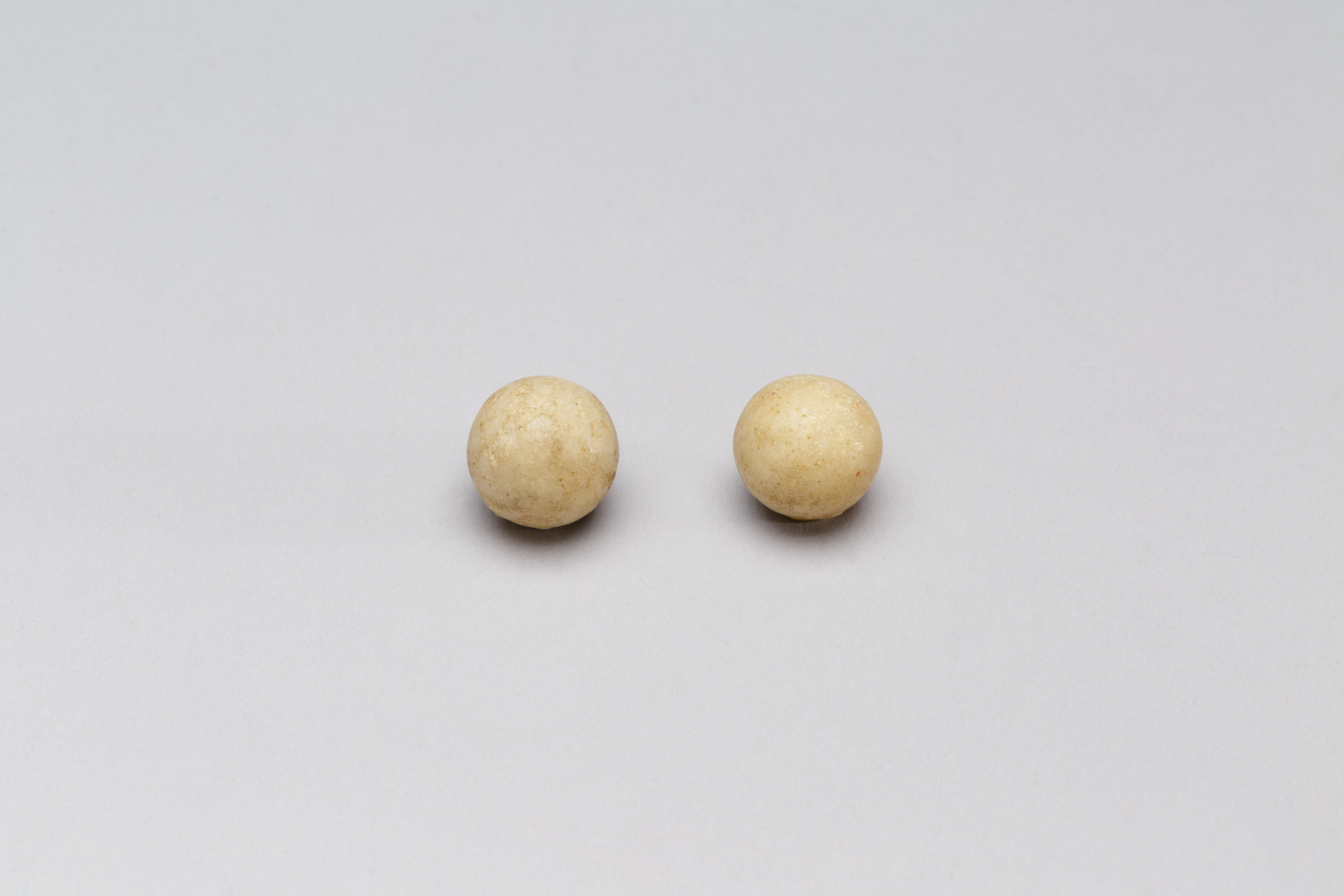 Two Beige Round Balls on Gray Background — White Backgrounds