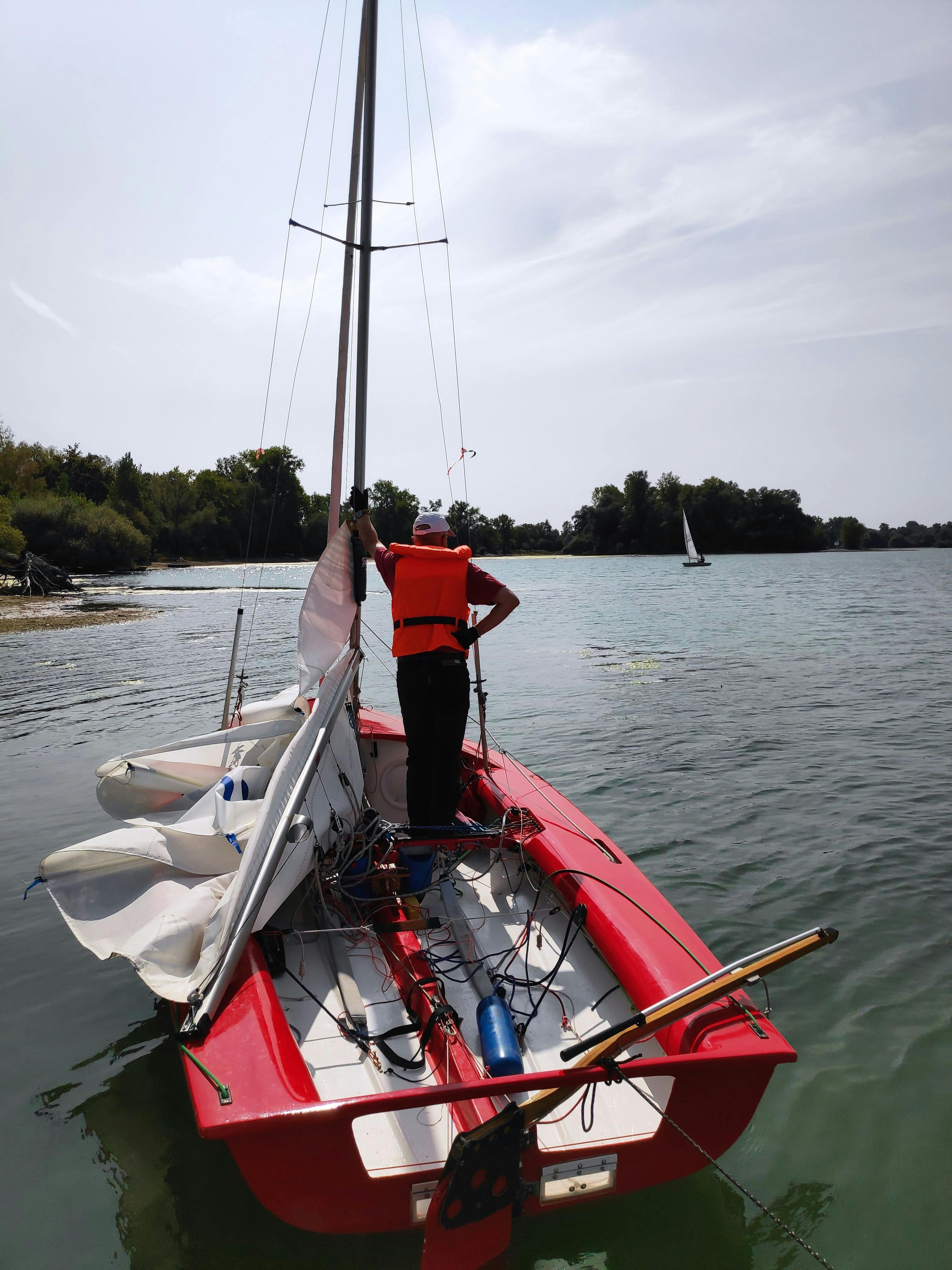 Man Preparing Sailboat on Lake
