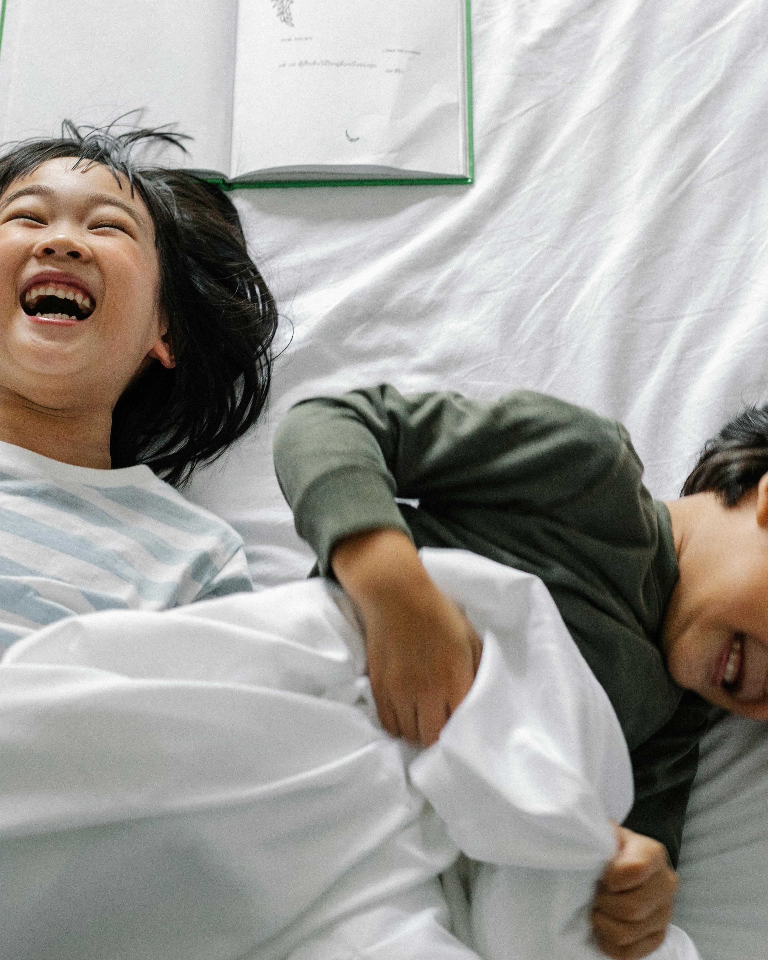 Two Happy Children Laughing in Bed