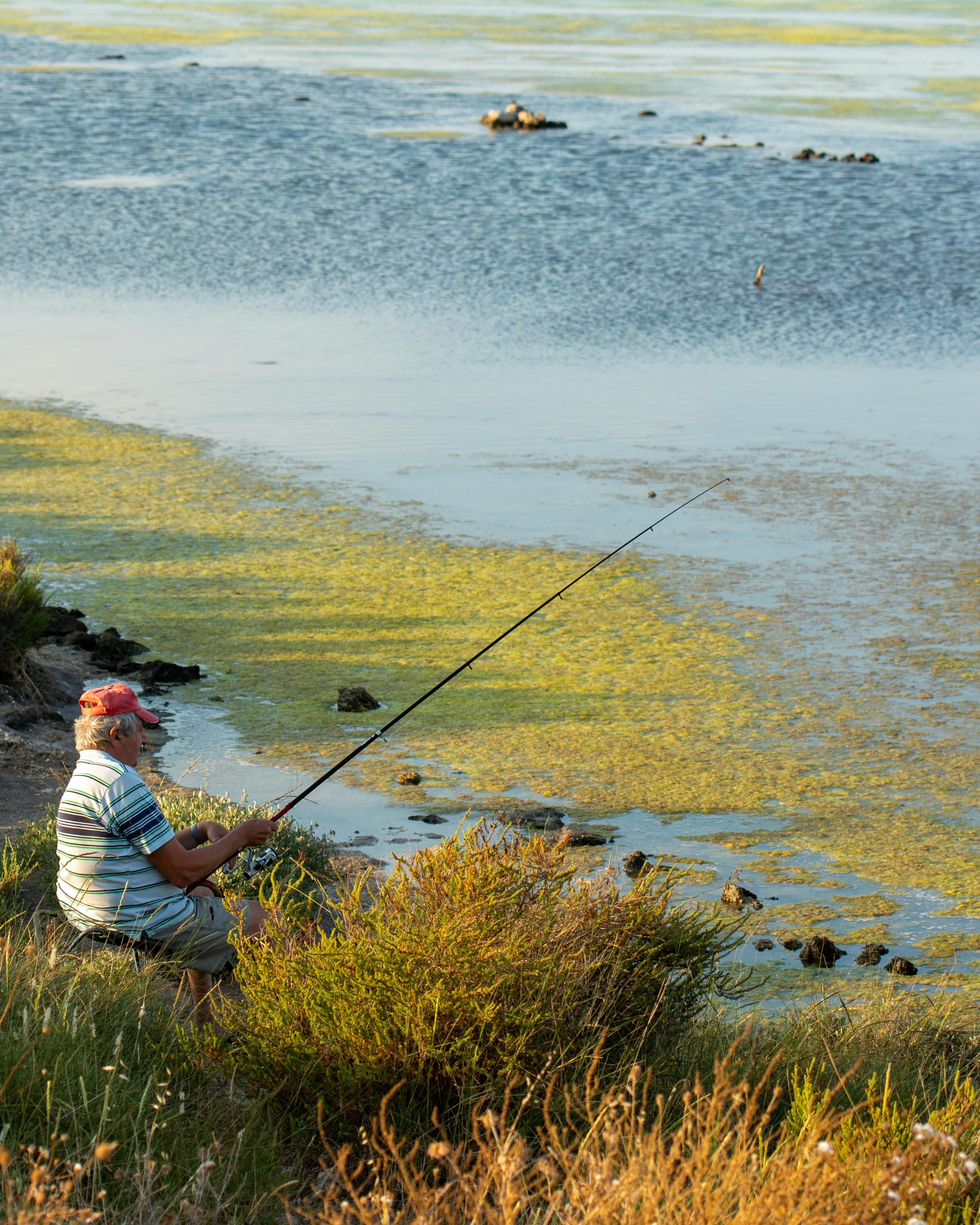 Senior Man Fishing by Shallow Water