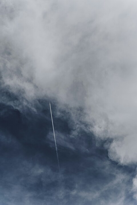 Airplane Contrails In Cloudy Sky